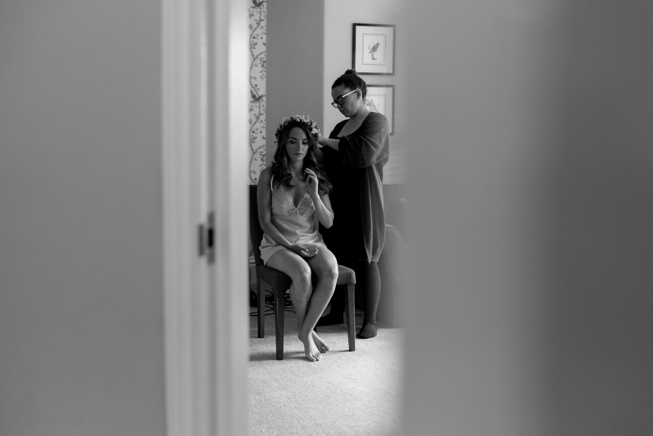 Bride sitting in the door way having her hair done