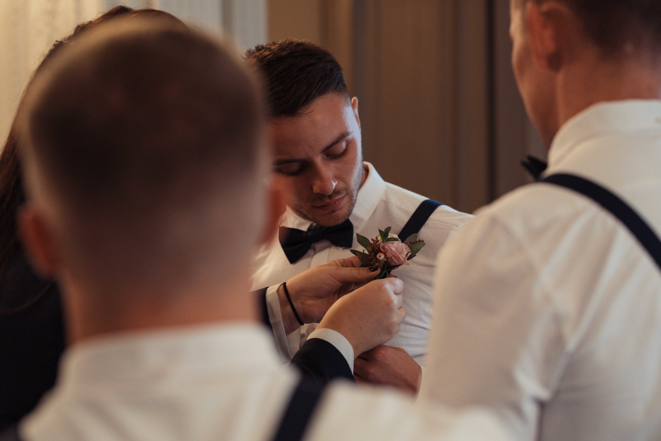 The groom in the Belsfield has his button hole put on before the wedding
