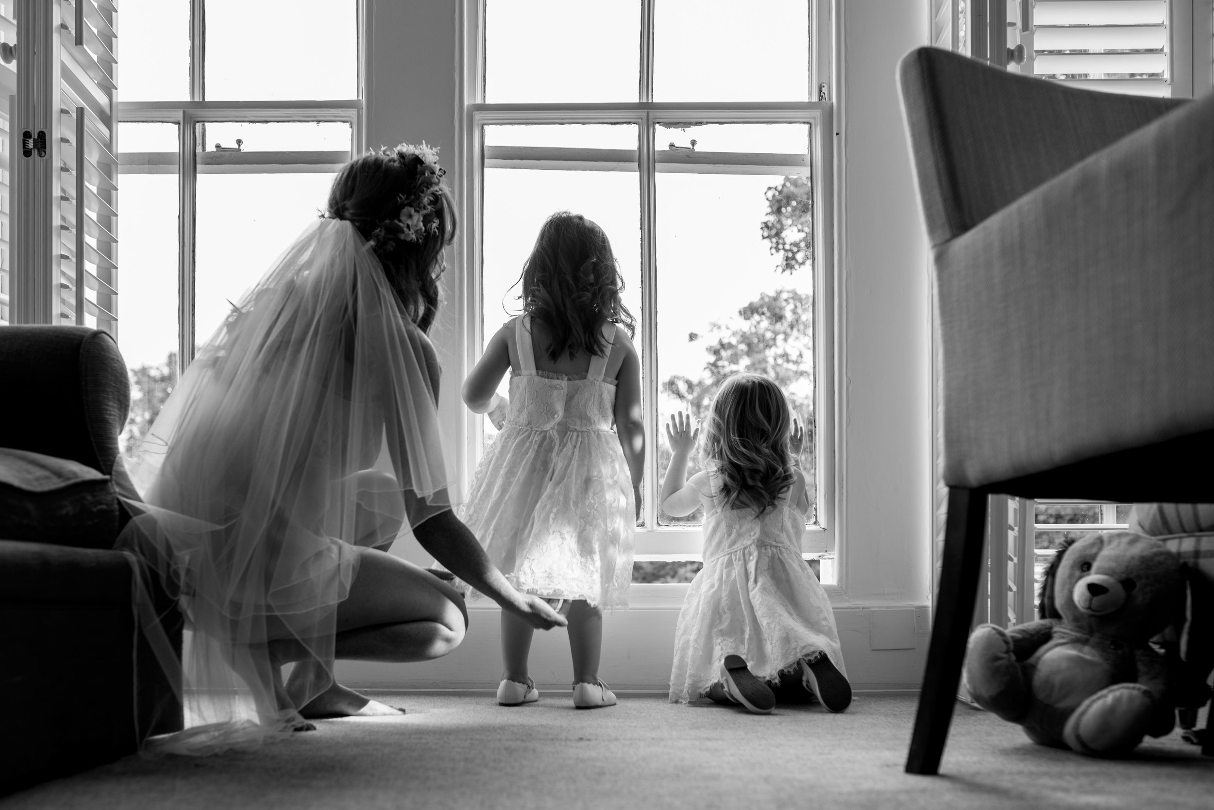 The bride stands in the bedroom window with her flower girls