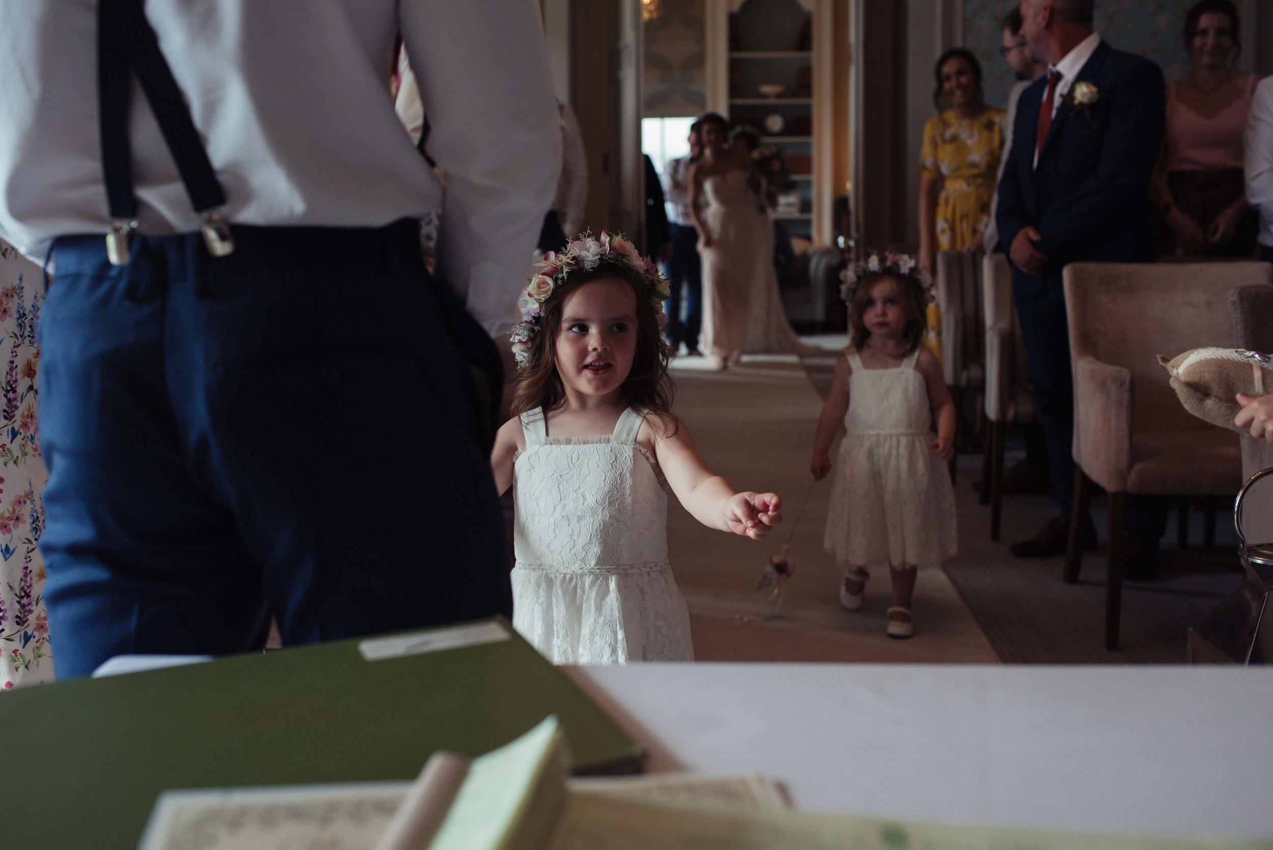 The flower girl, daughter of the bride and groom, walks up the aisle to her dad