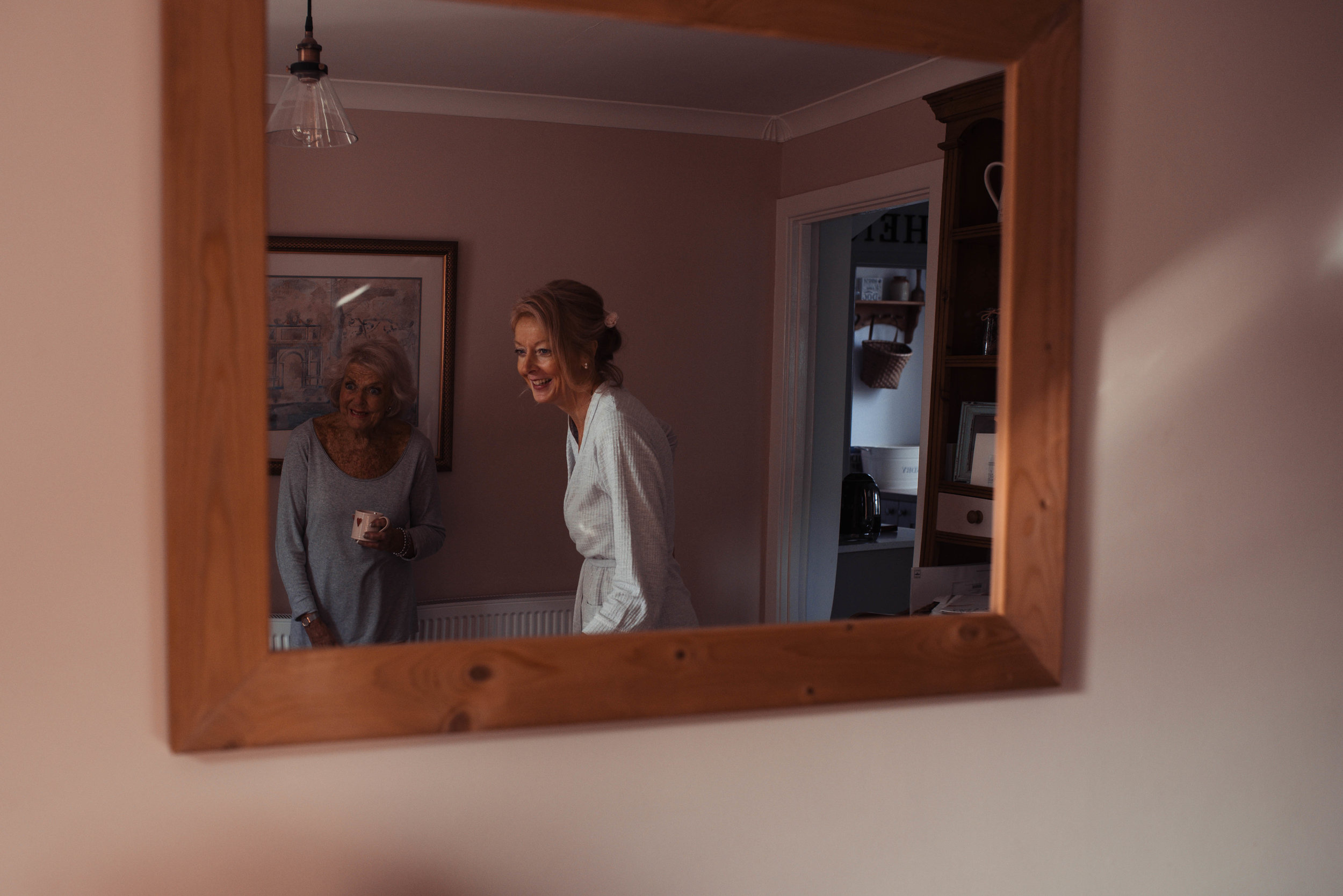 The bride and her mother as seen through a mirror in the kitchen dining room