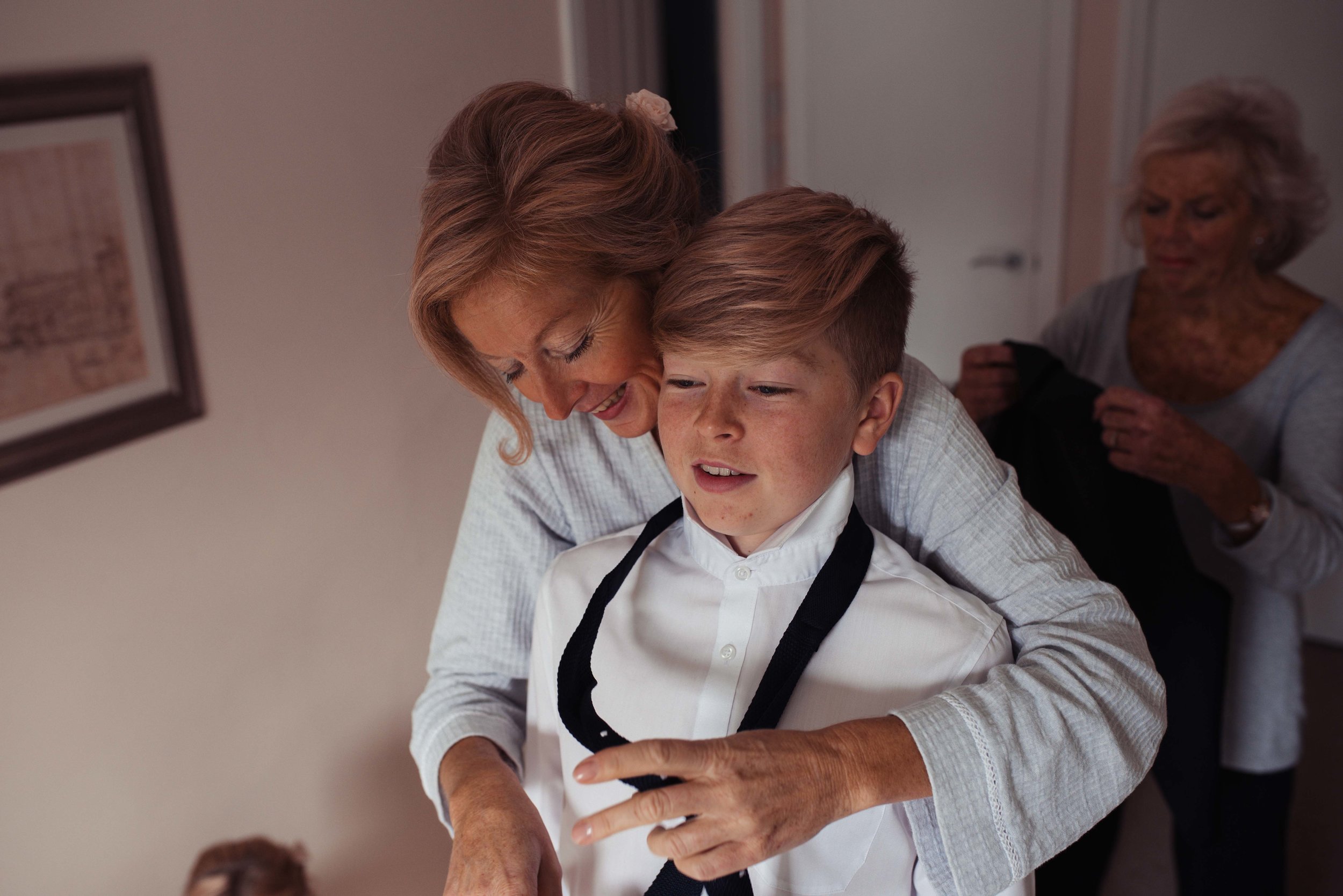 The bride stands with her son to help him get dressed