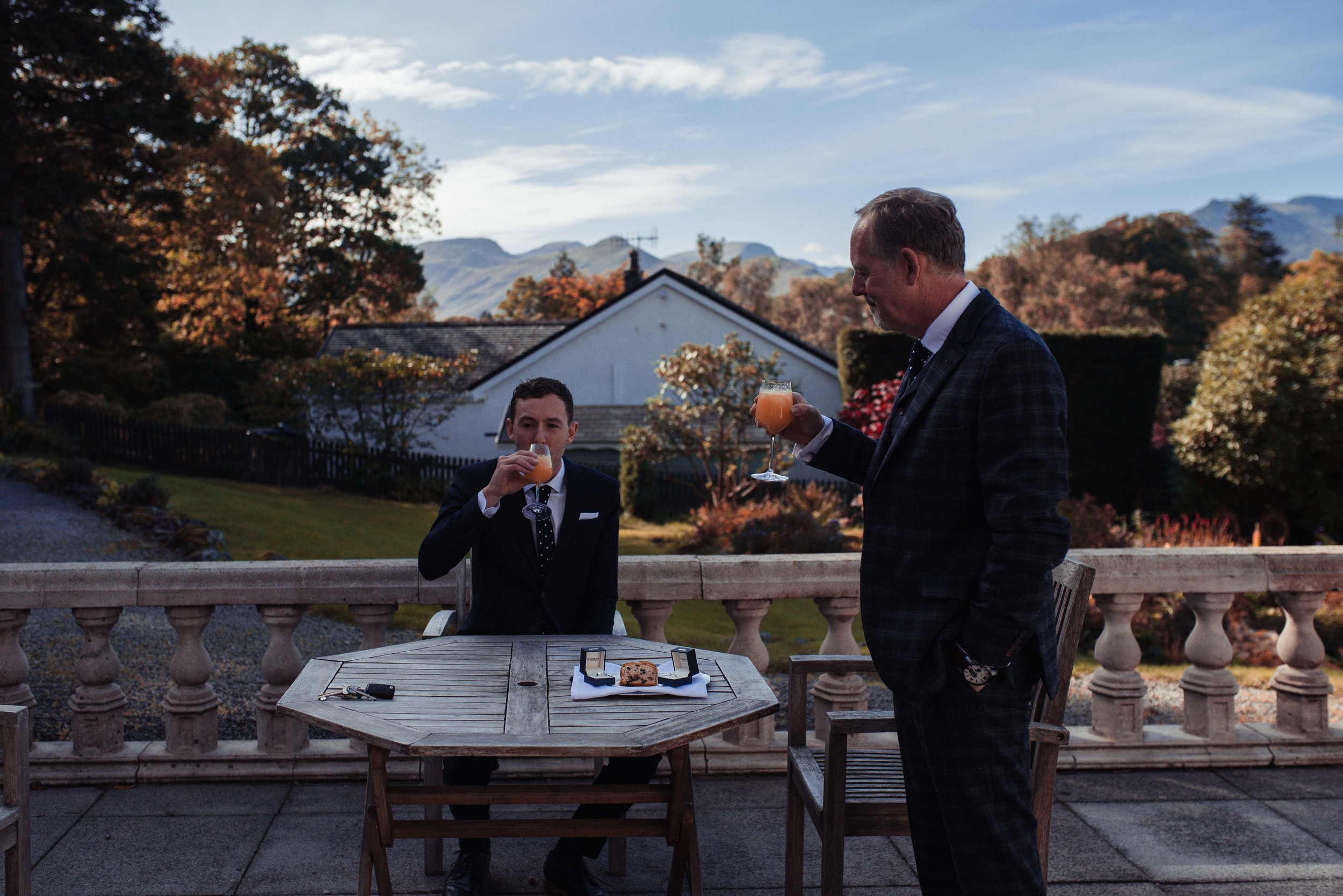 The groom and his best man enjoy orange juice and cake on the terrace before the wedding