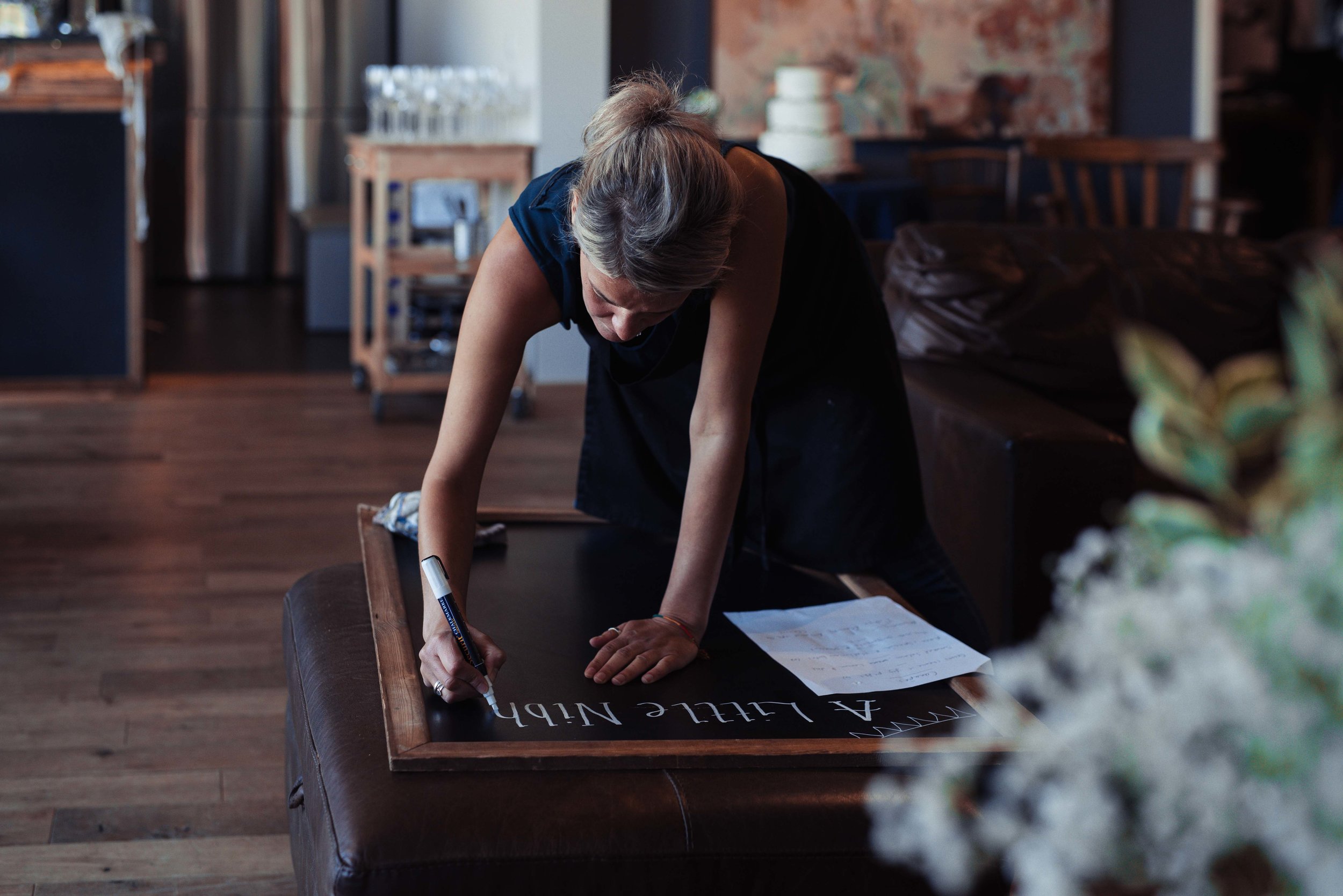 A lady at the wedding venue creates a sign with the food menu on it