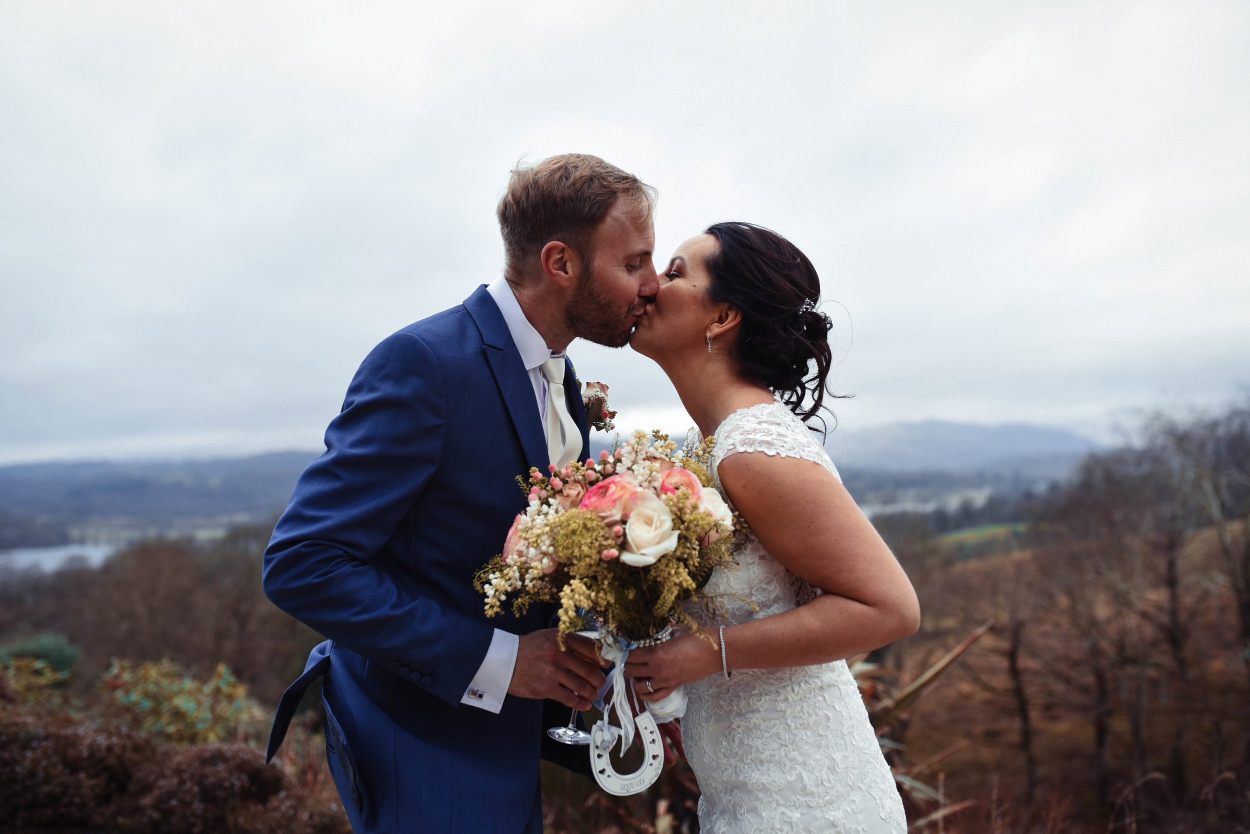 The bride and groom share a kiss with Windermere in the background