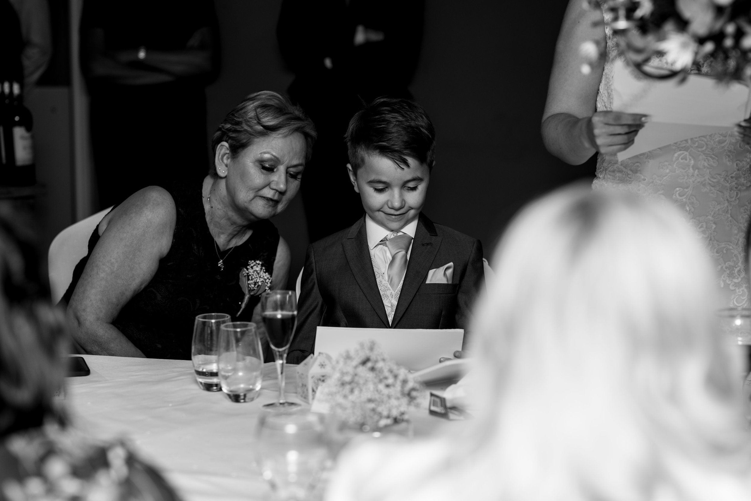 The brides mum and their son look at a photo during the speeches