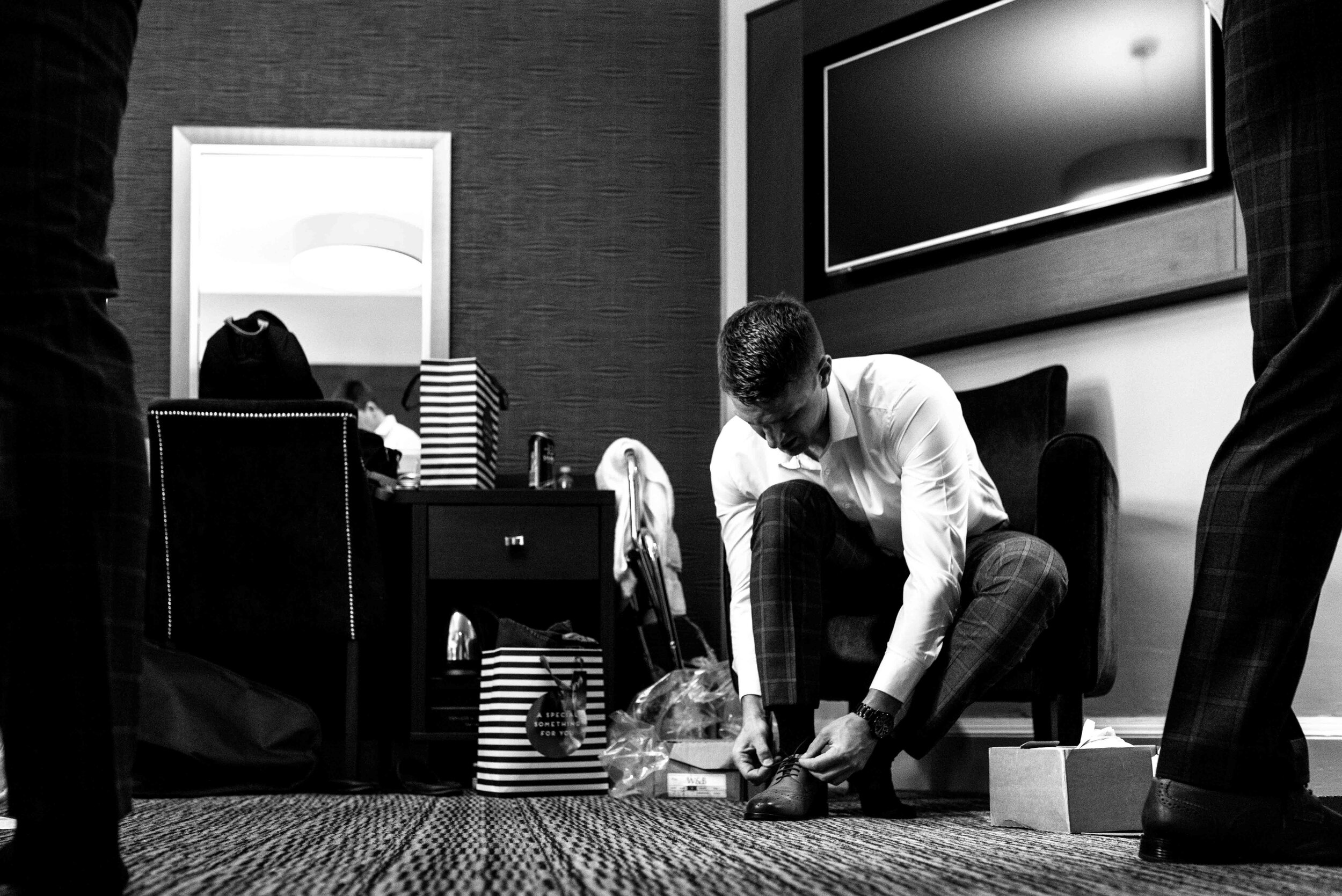 Groom putting his shoes on before the wedding