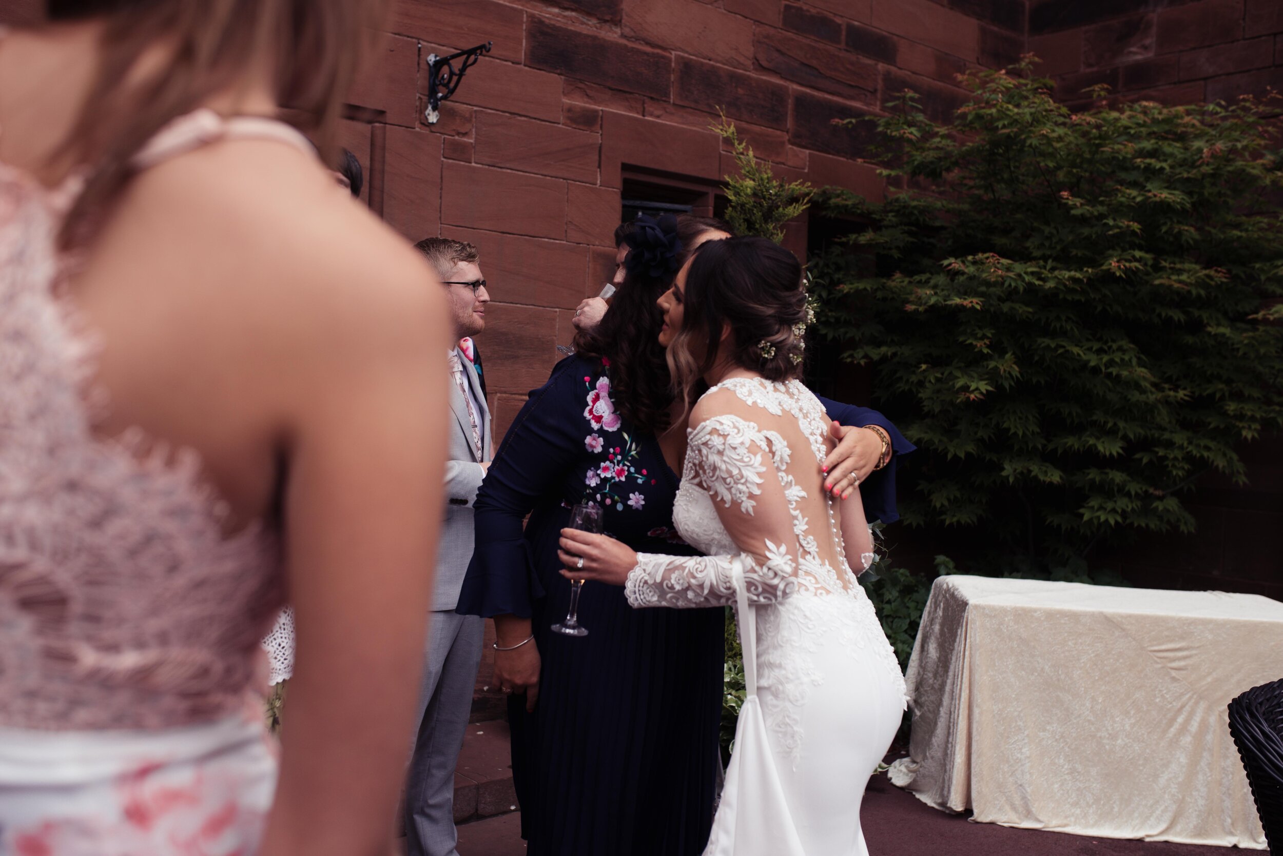 A wedding guest dressed in purple gives the bride a cuddle outside Abbey House