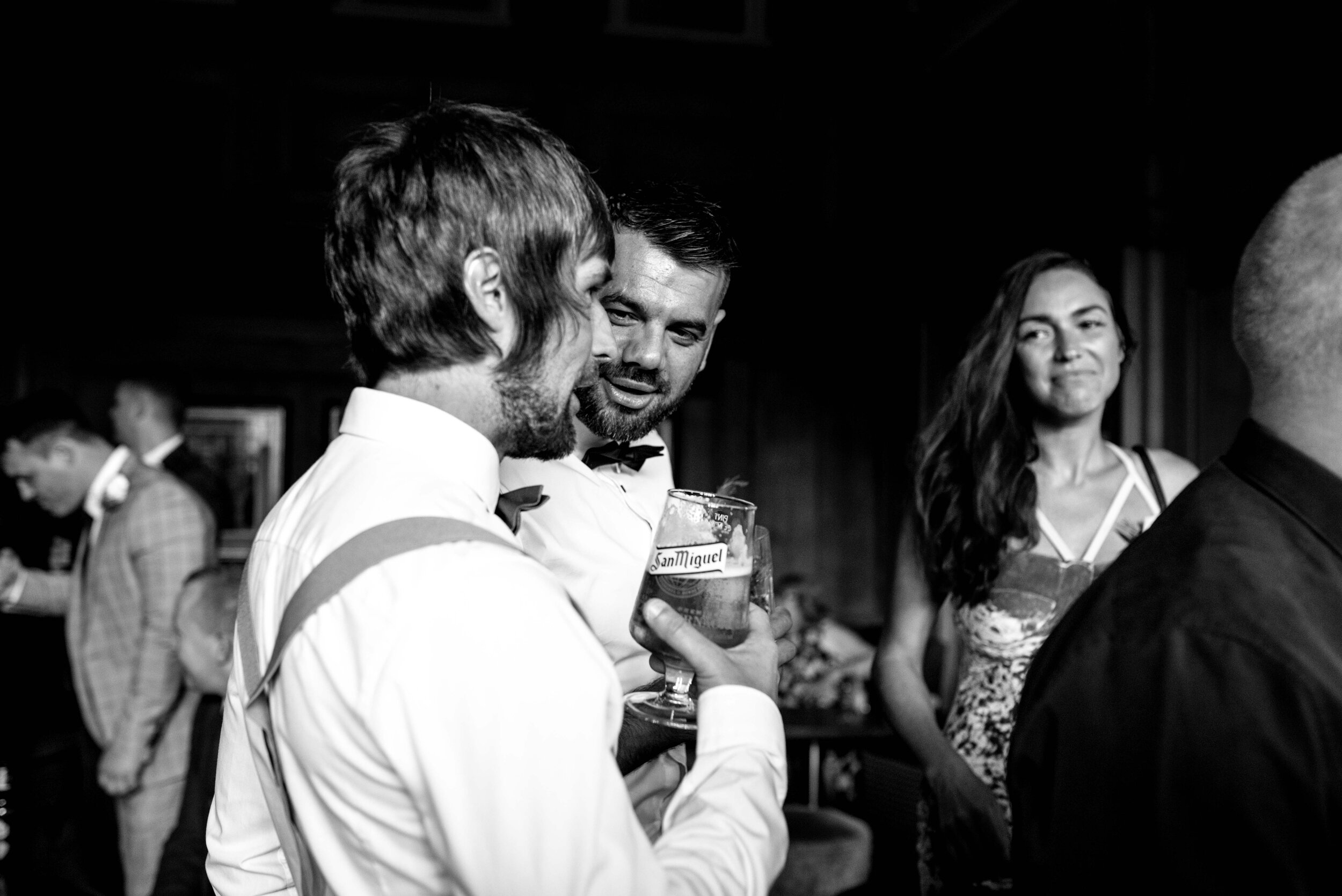 Three wedding guests chat at the bar at Abbey House