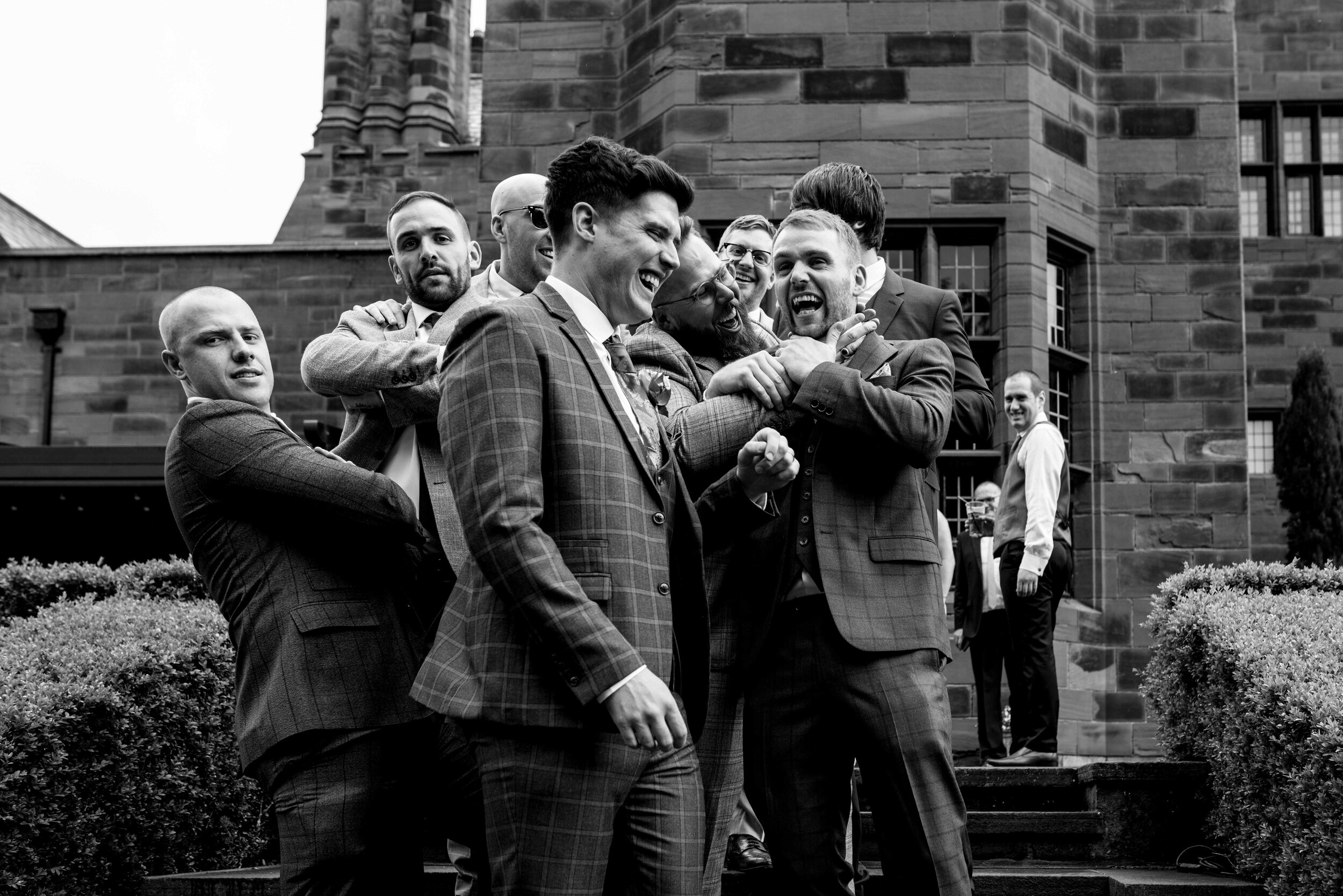 The groom and his groomsmen messing around together on the Abbey House steps