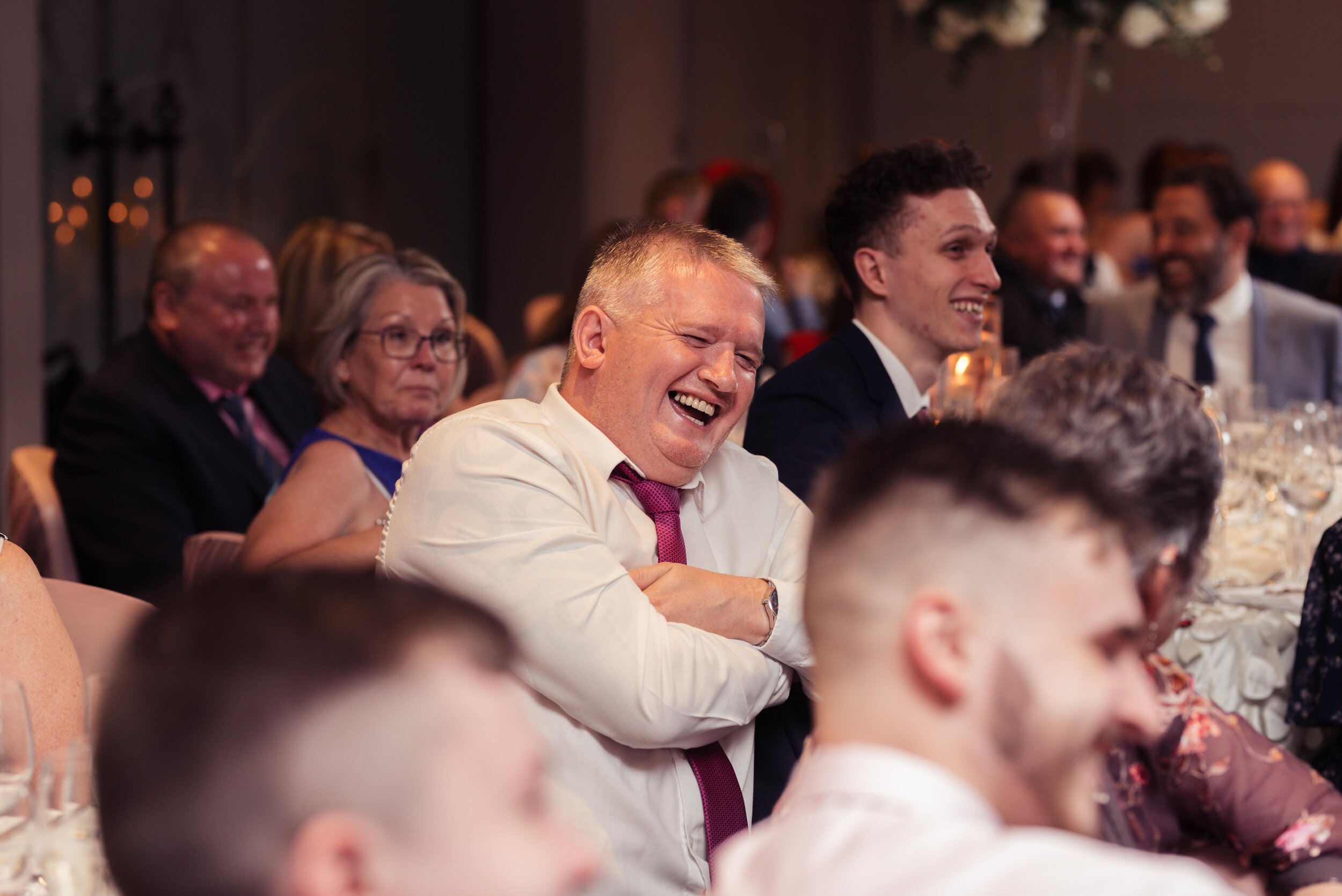 Male wedding guest laughing during the speeches