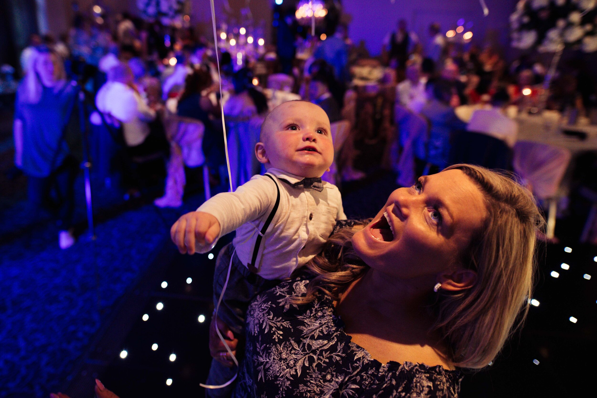 Young baby and his mum looking at the disco lights on the dance floor
