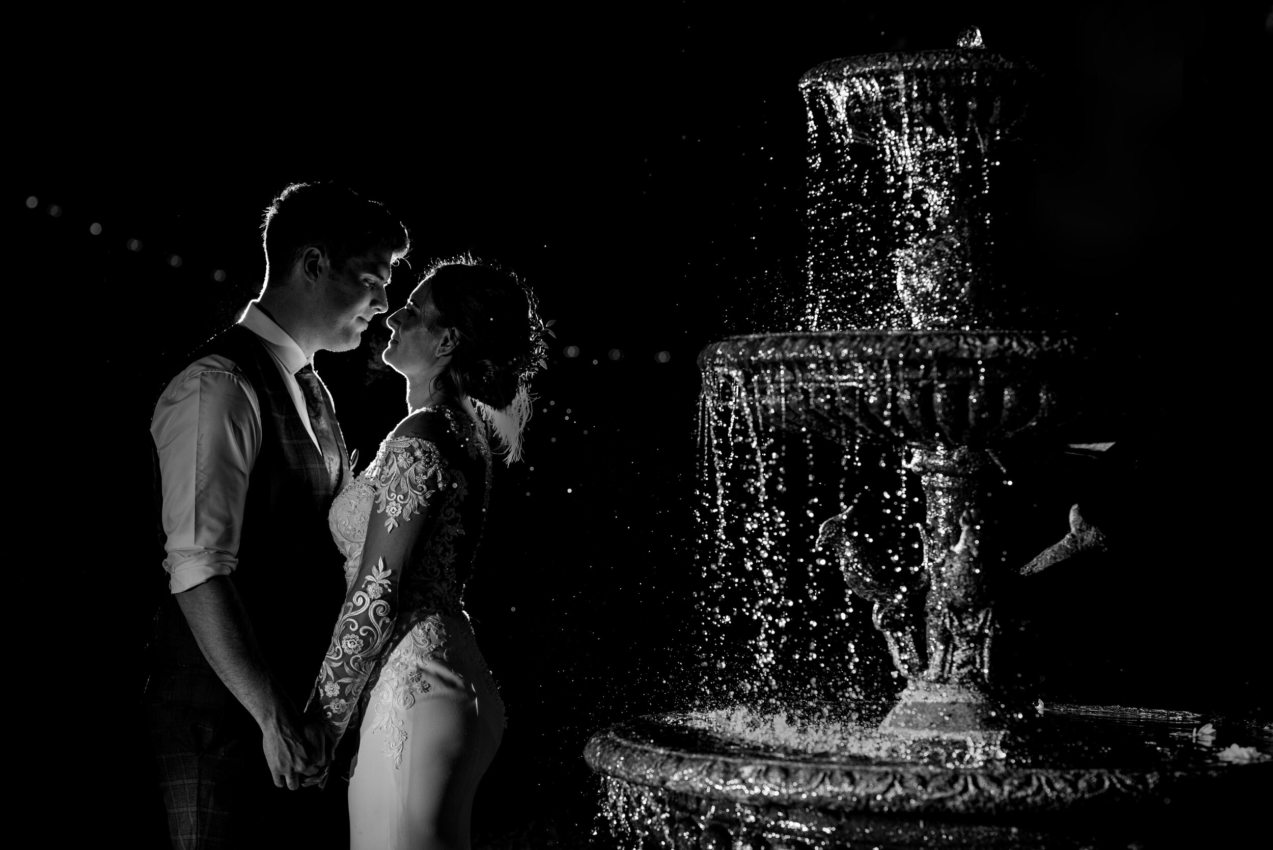 Backlit shot of the bride and groom at the fountain outside Abbey House