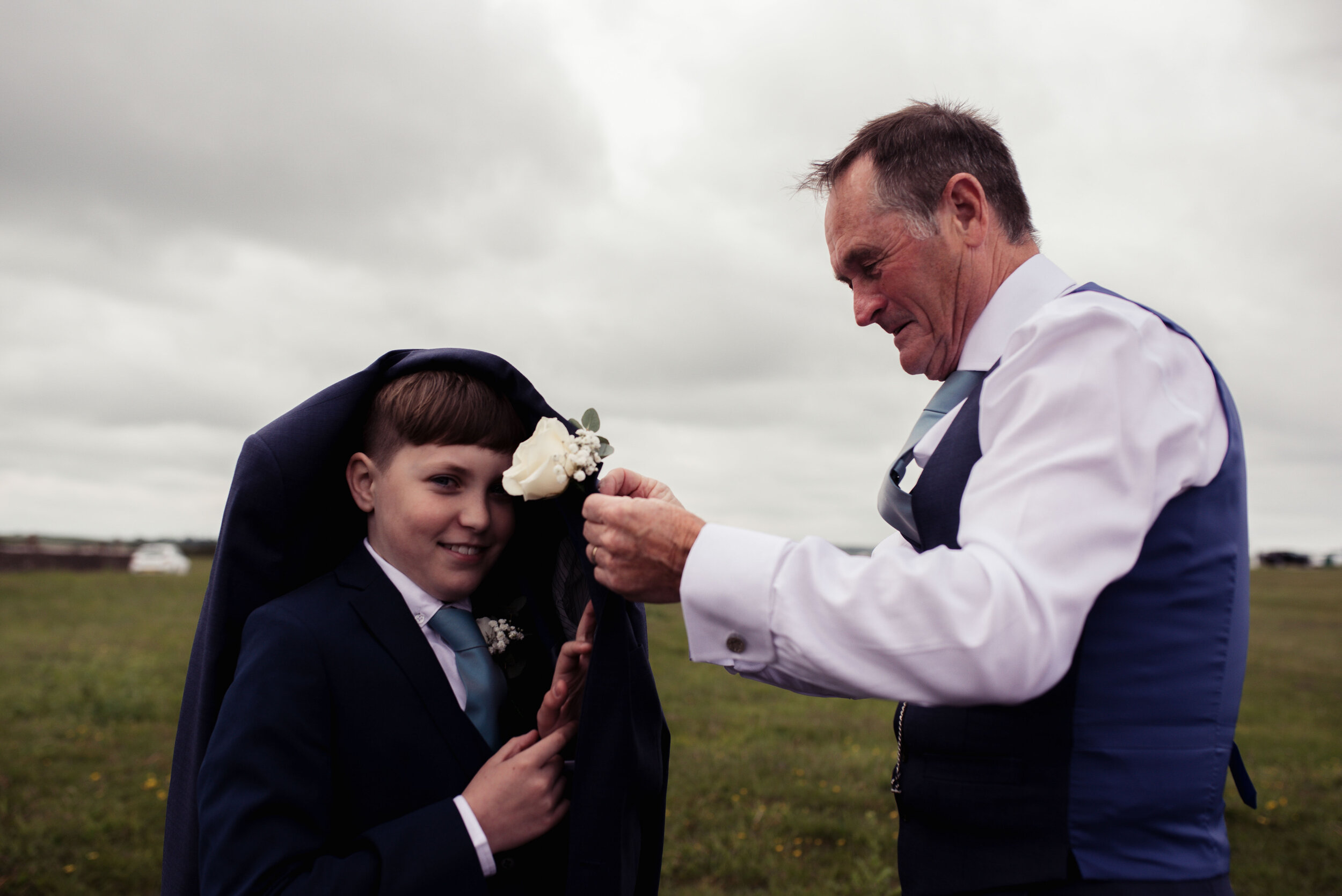 Best man helping put a button hole on the son of the groom