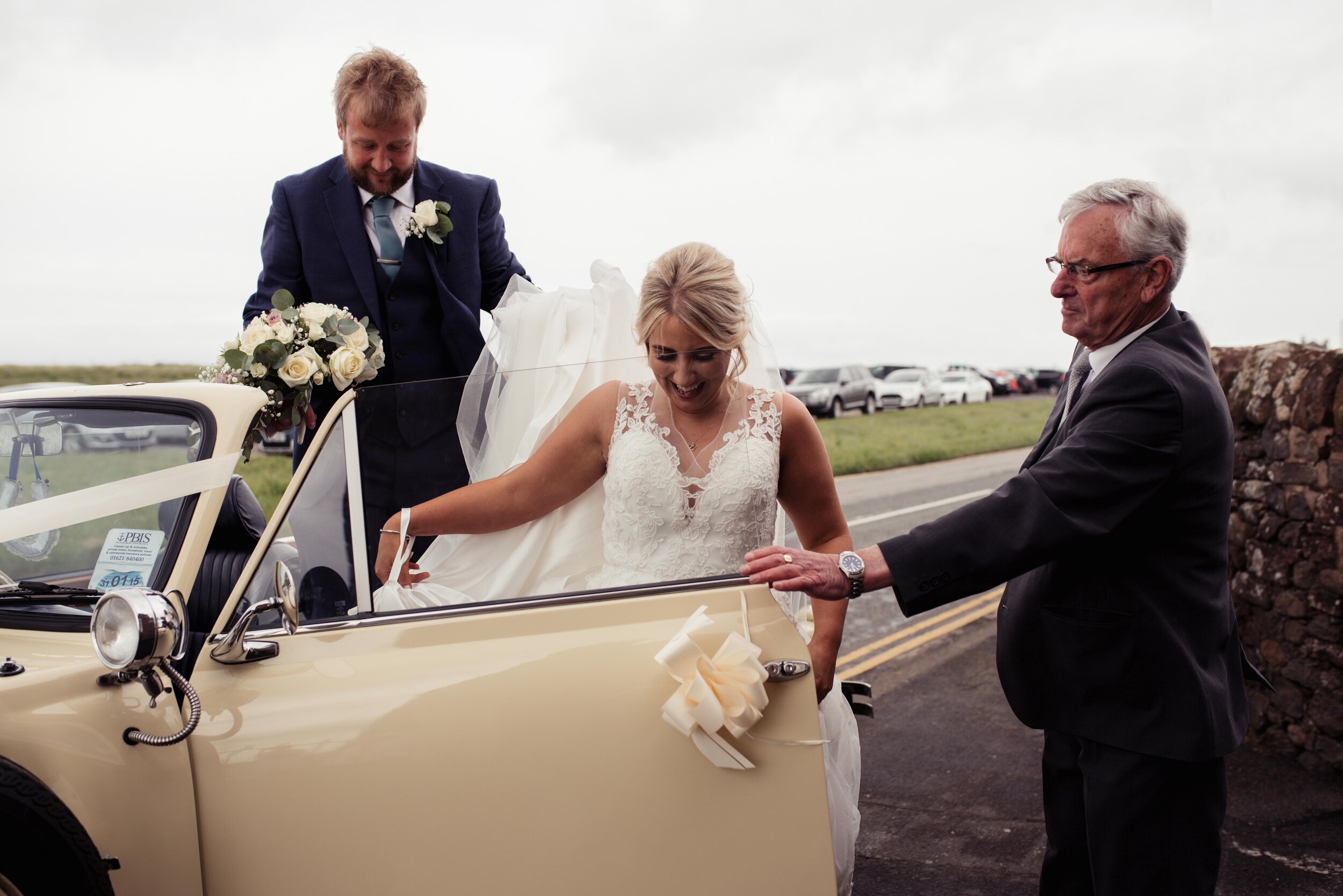 The bride is helped out of the car outside her Allonby church