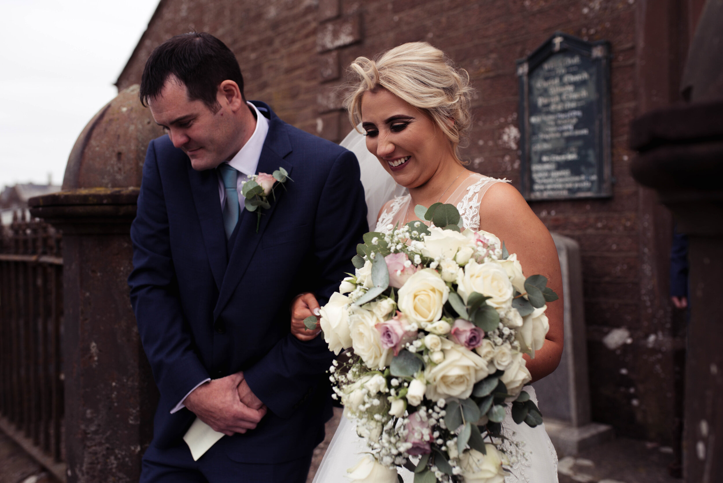 The bride and groom step out of their Cumbria church