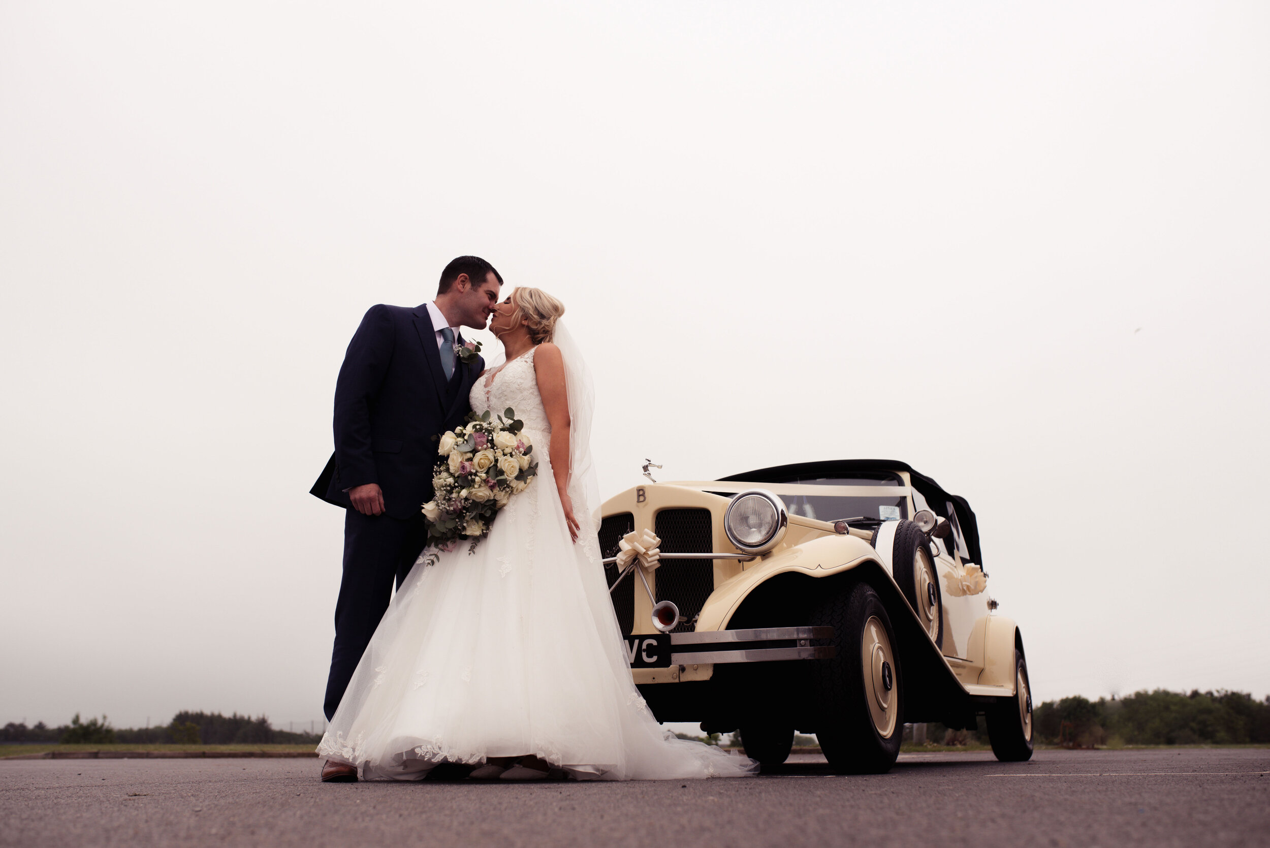 The bride and groom stand outside their wedding car at whitehaven golf club