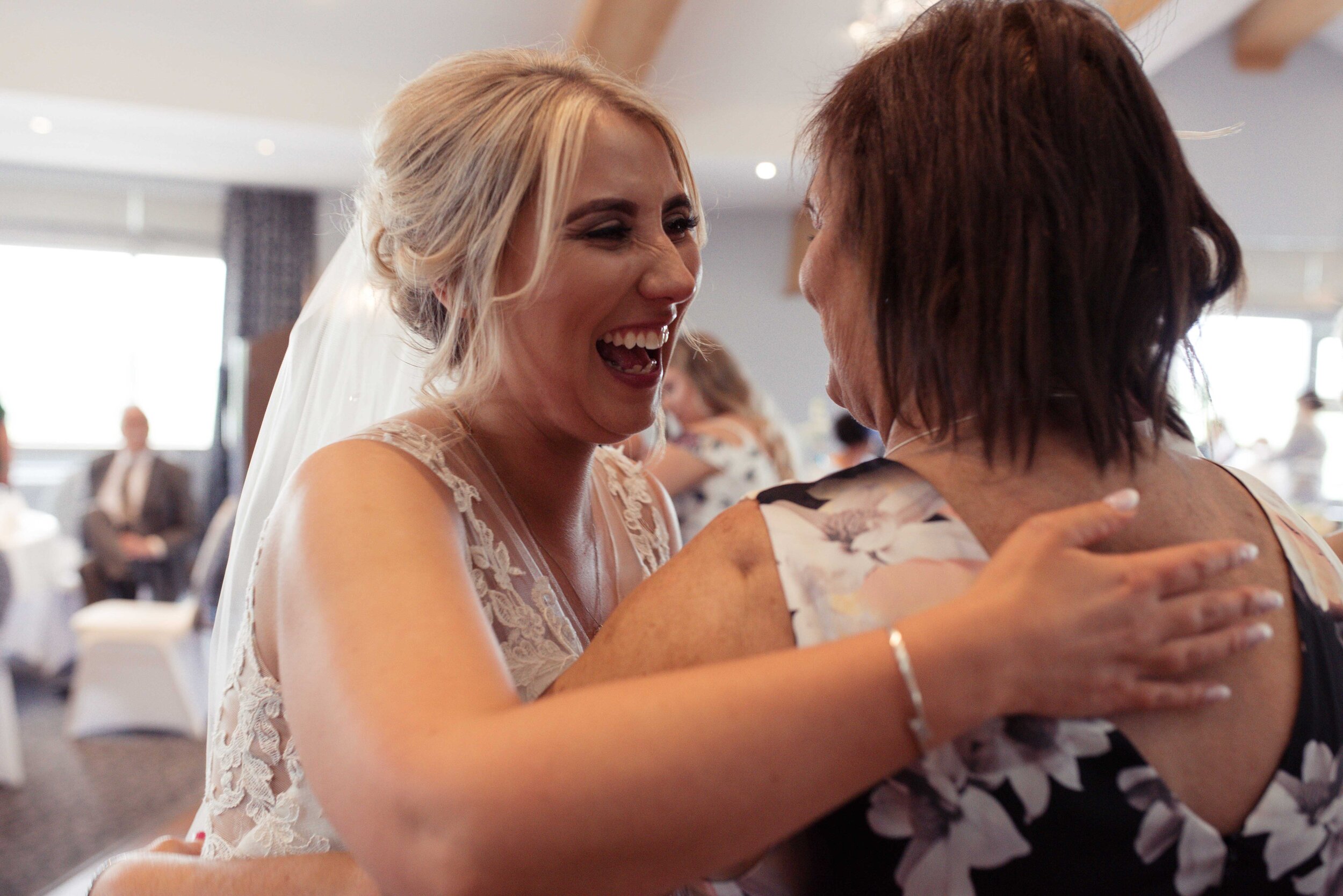 The bride greats a wedding guest with a big smile on her face