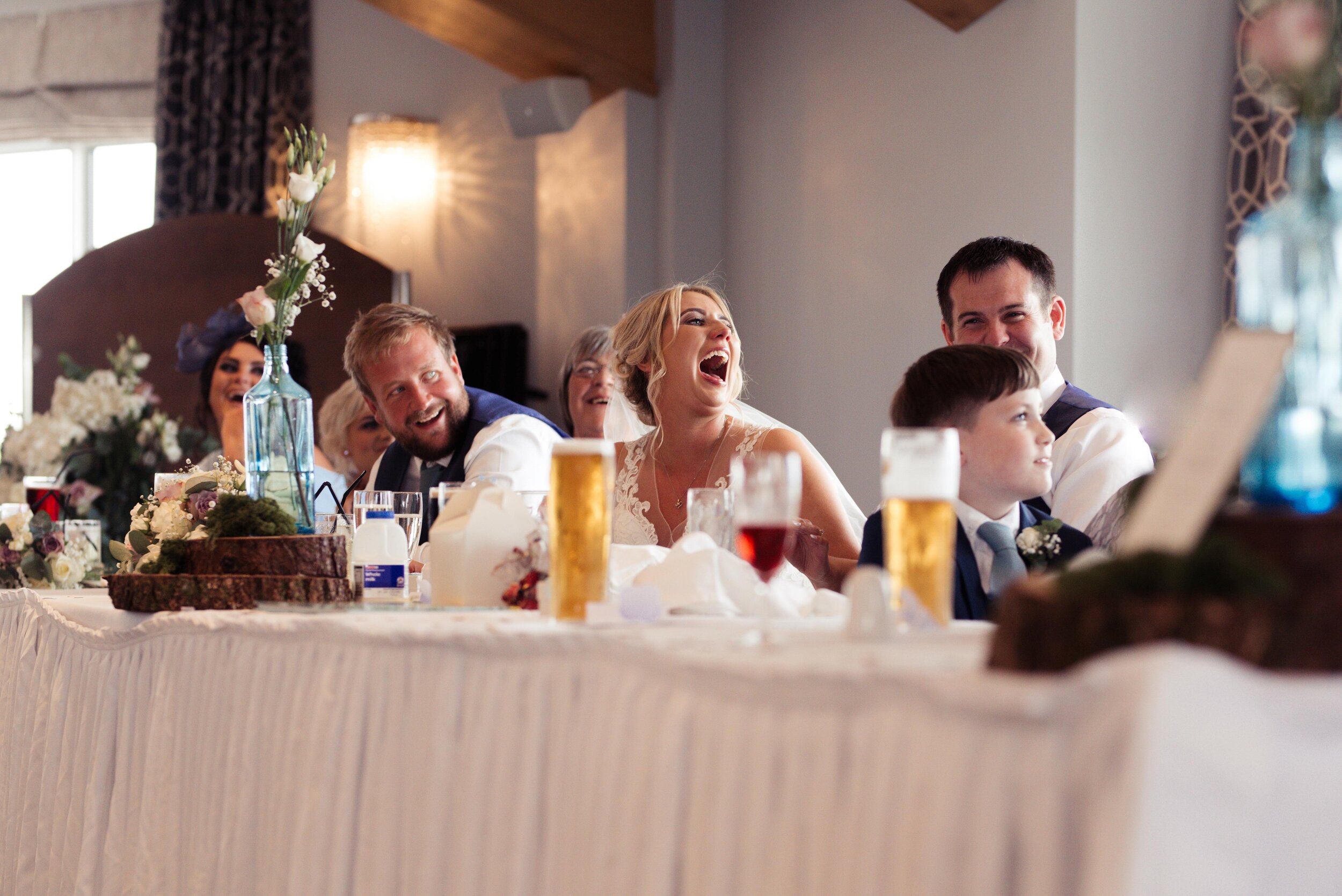The bride has a shocked laughing face during the speeches