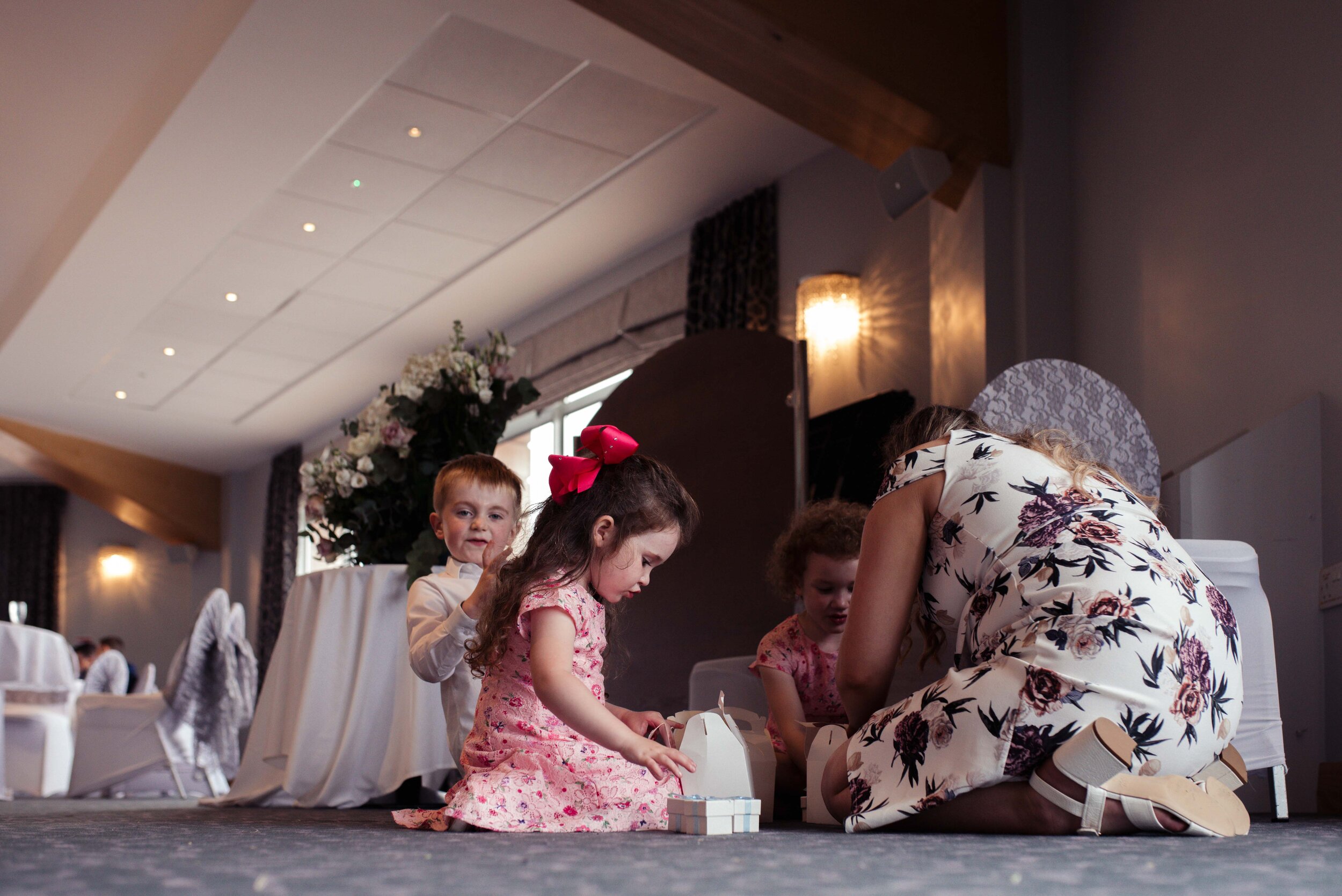Children sit on the floor of the wedding venue and play games together