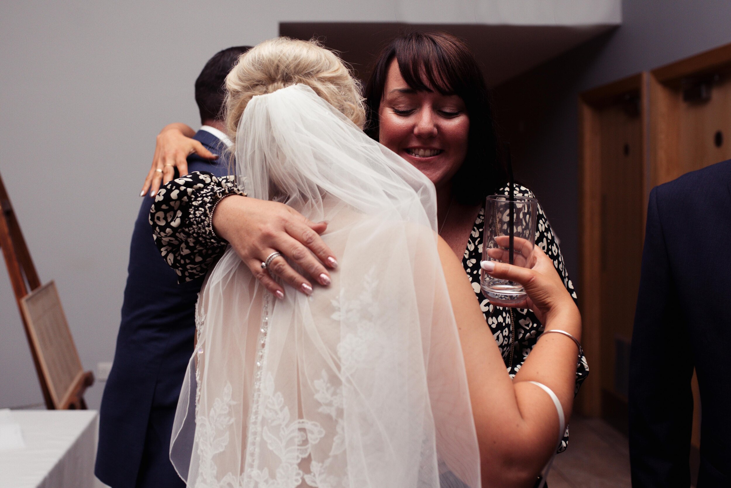 The bride gives one of the evening guests a big hug by the door