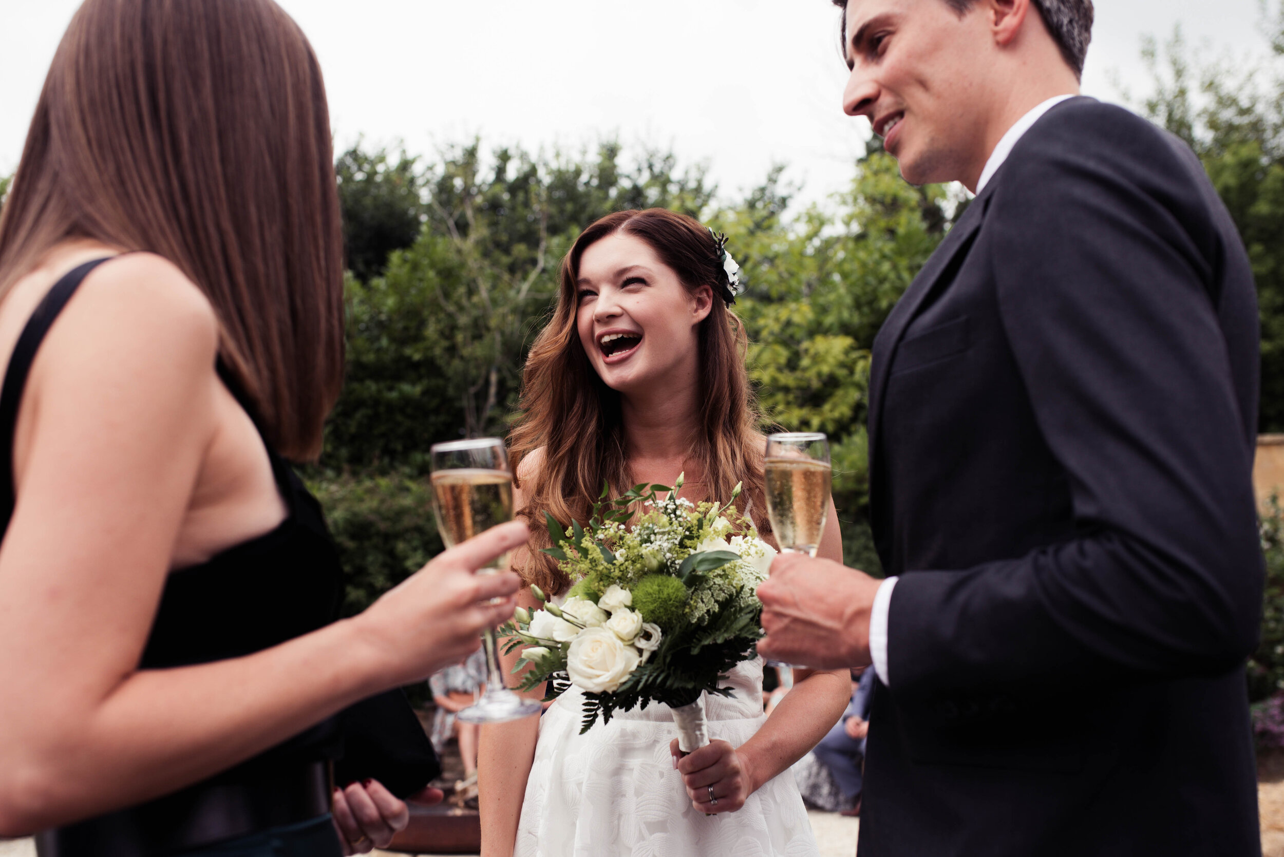 The bride shares a beaming laugh with two other wedding guests