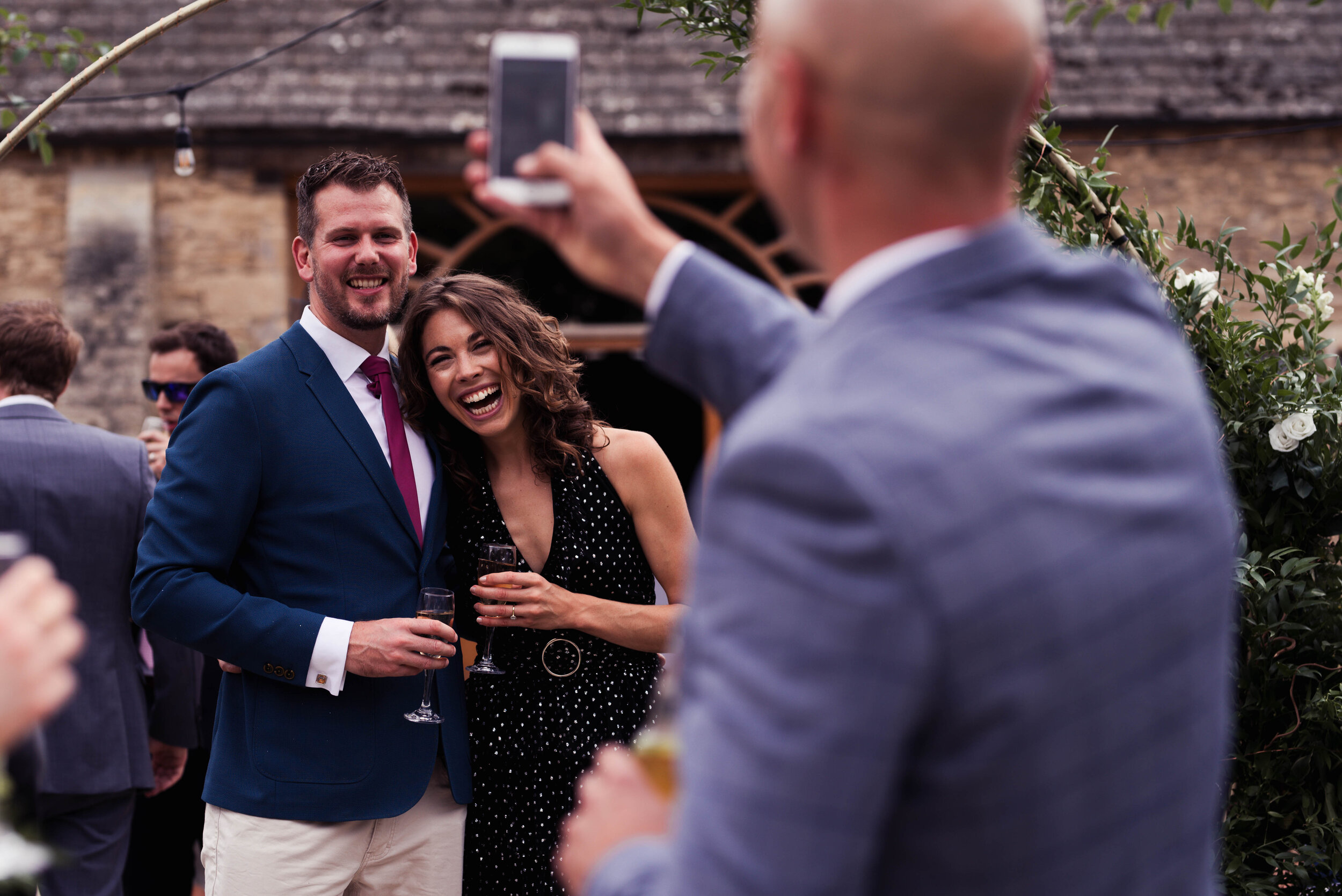 A male wedding guest takes a photo of another two guests
