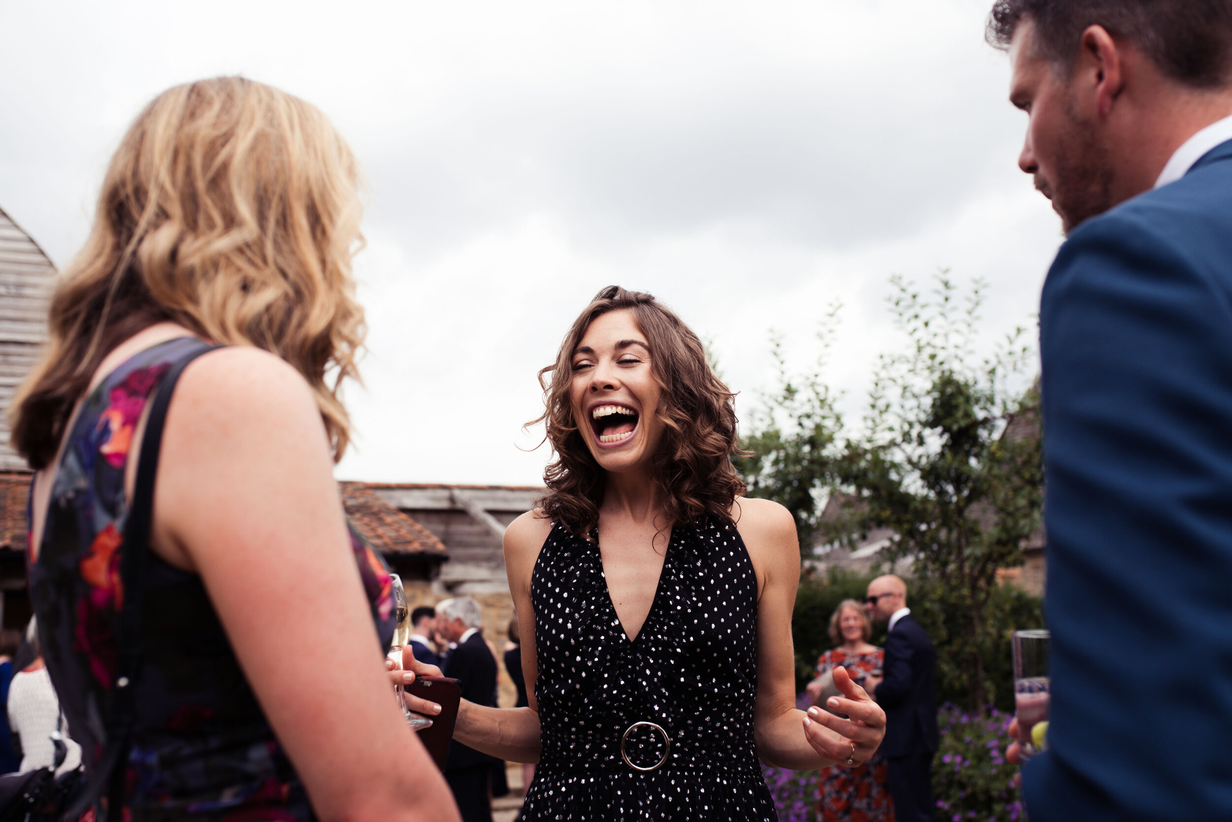 A wedding guest throws her hands in the air while laughing