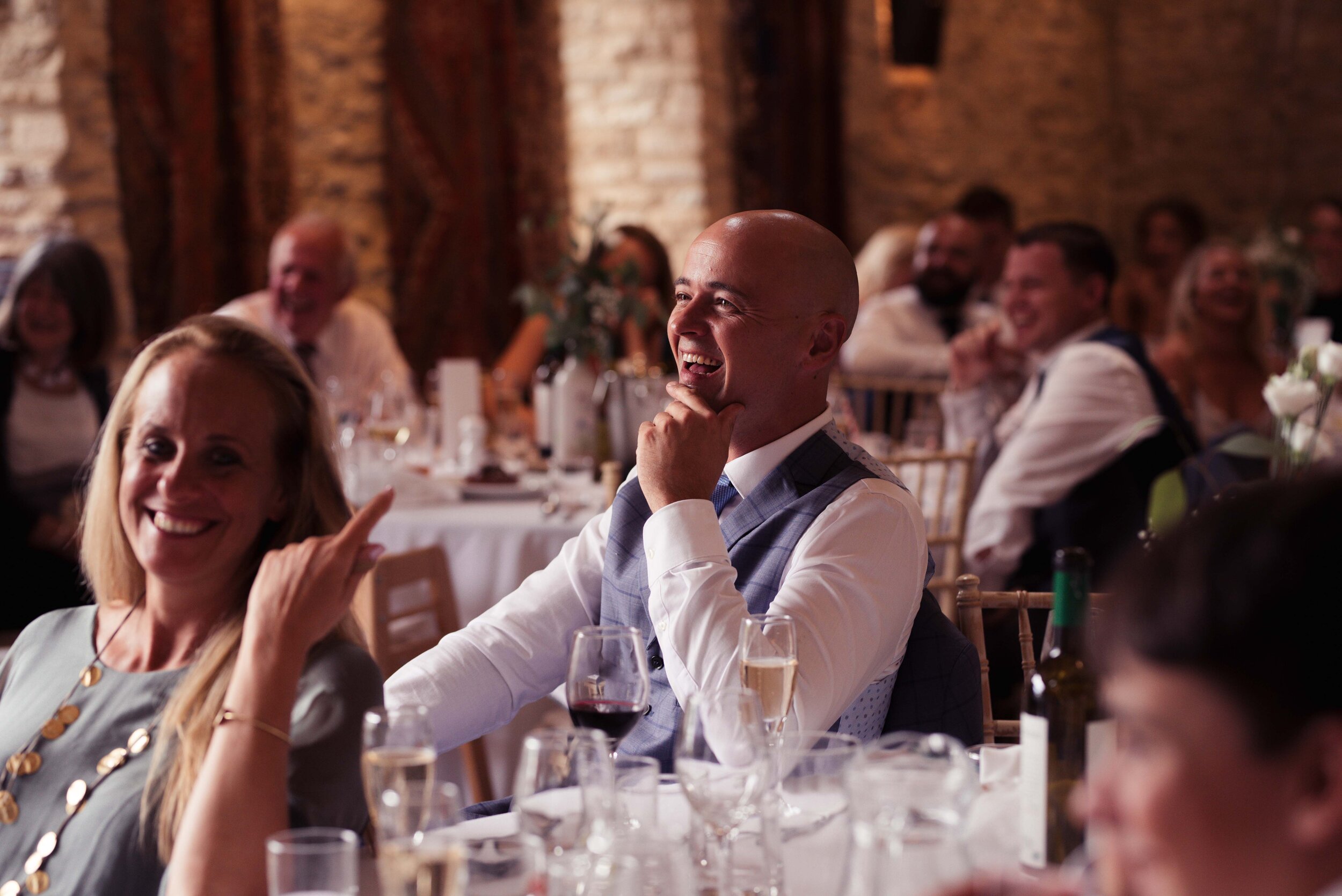 A gentleman wedding guest laughs during the best mans speech