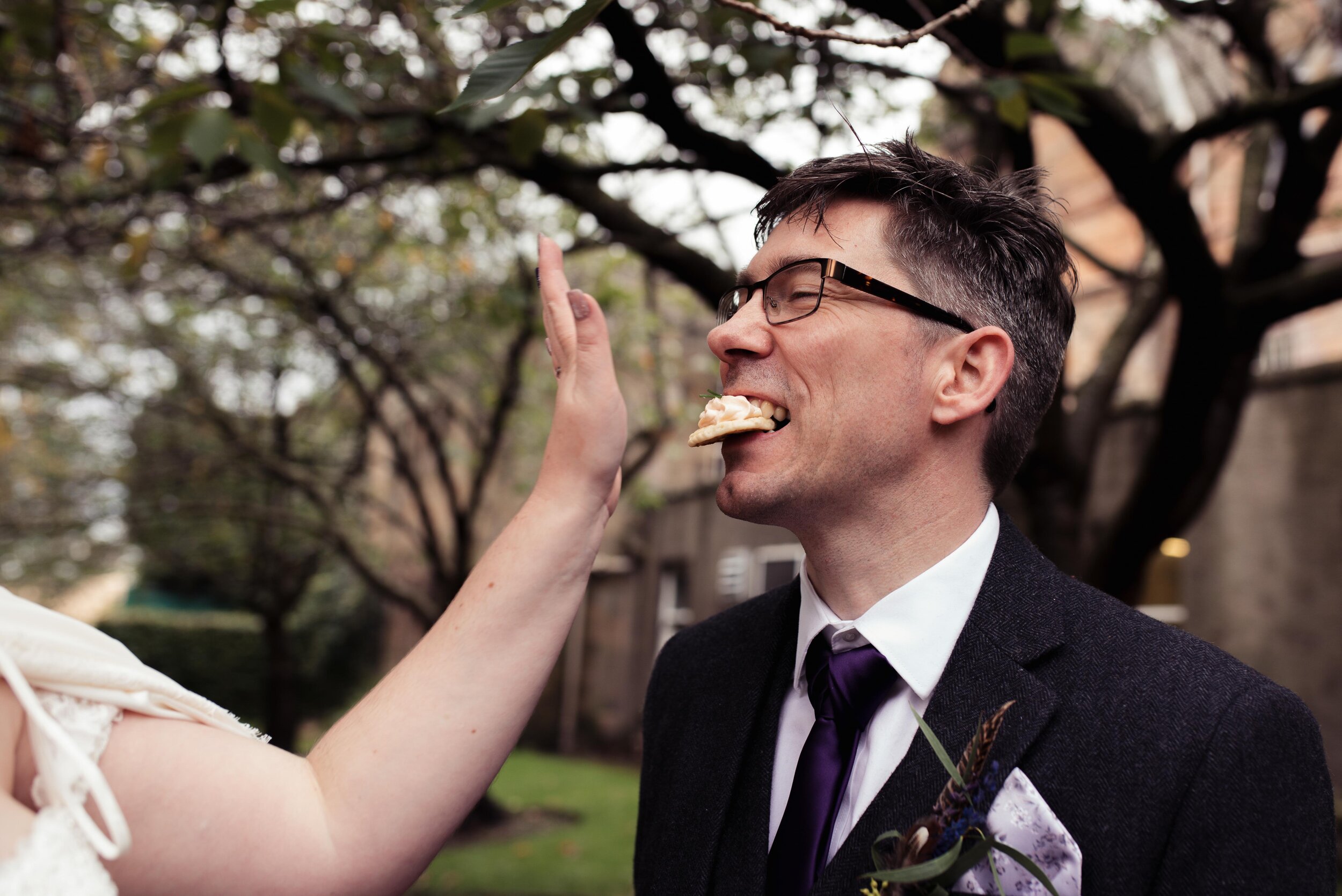 Bride shoving a canapes in the grooms mouth