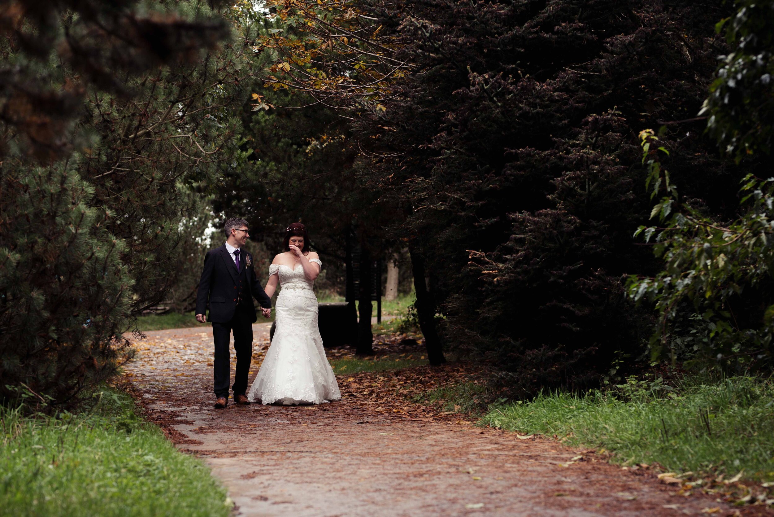 Bride and groom walking together through the trees during their portraits