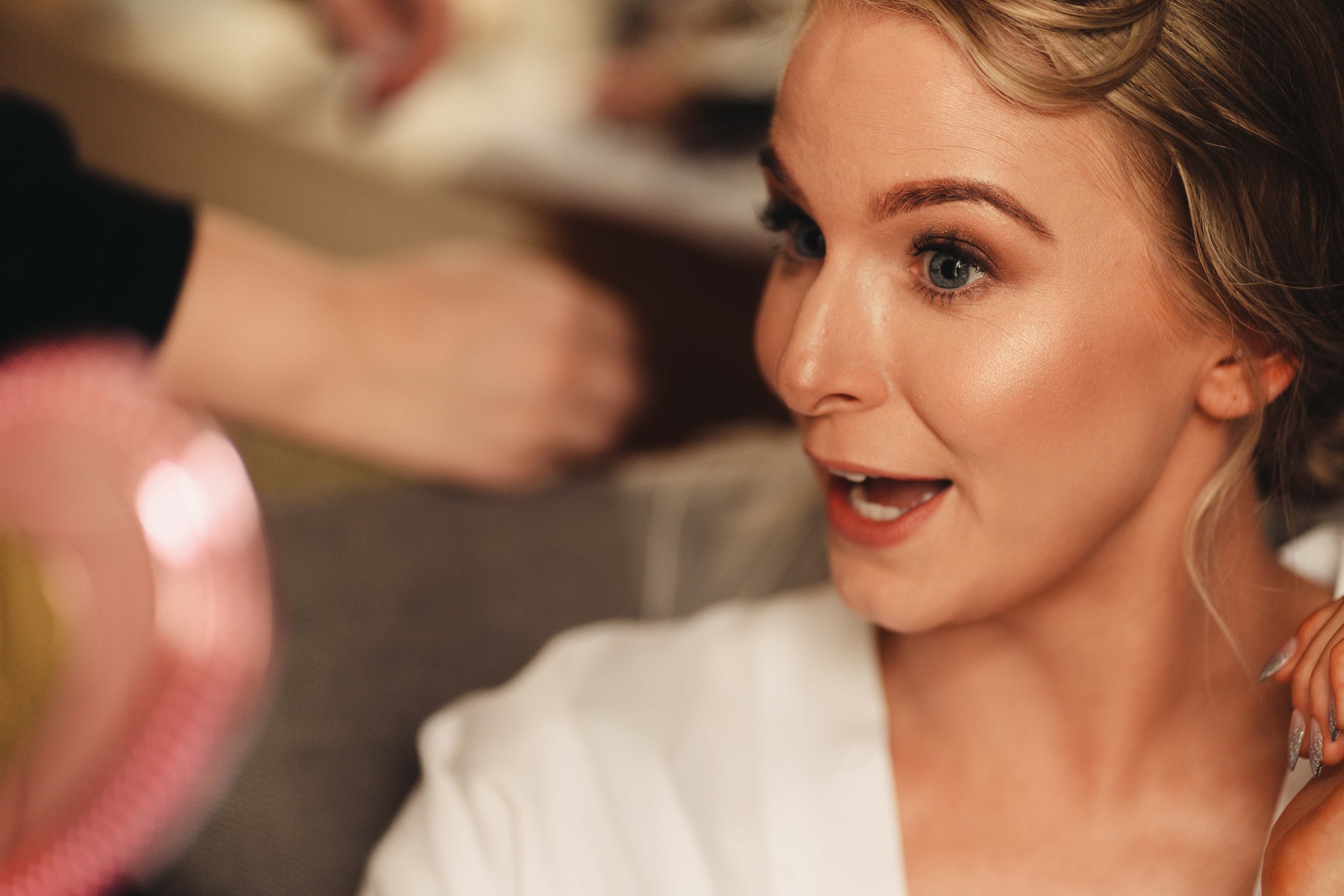 Bride happily looking at her makeup in the mirror