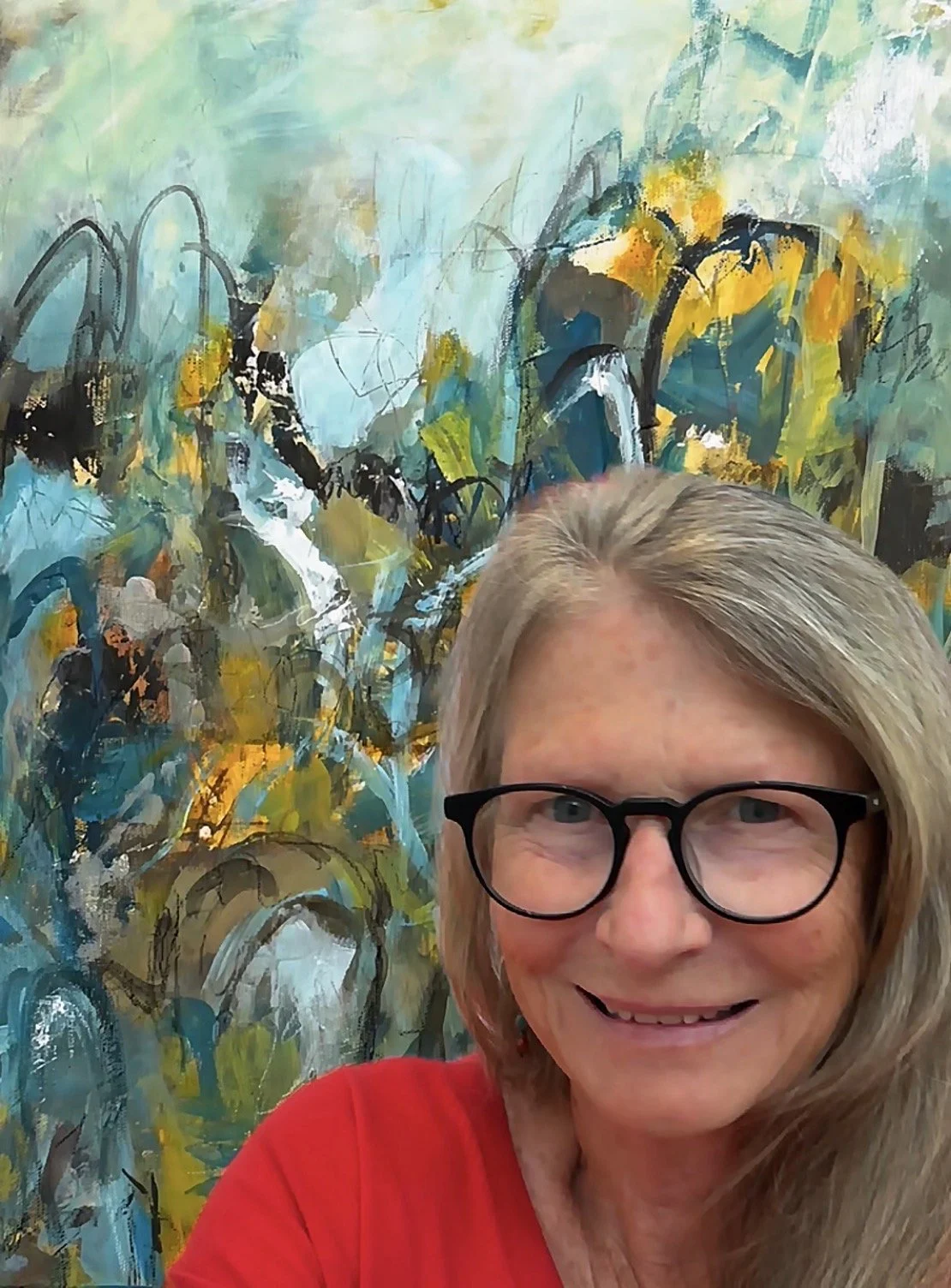 Lee Ghilain standing before one of her abstract paintings