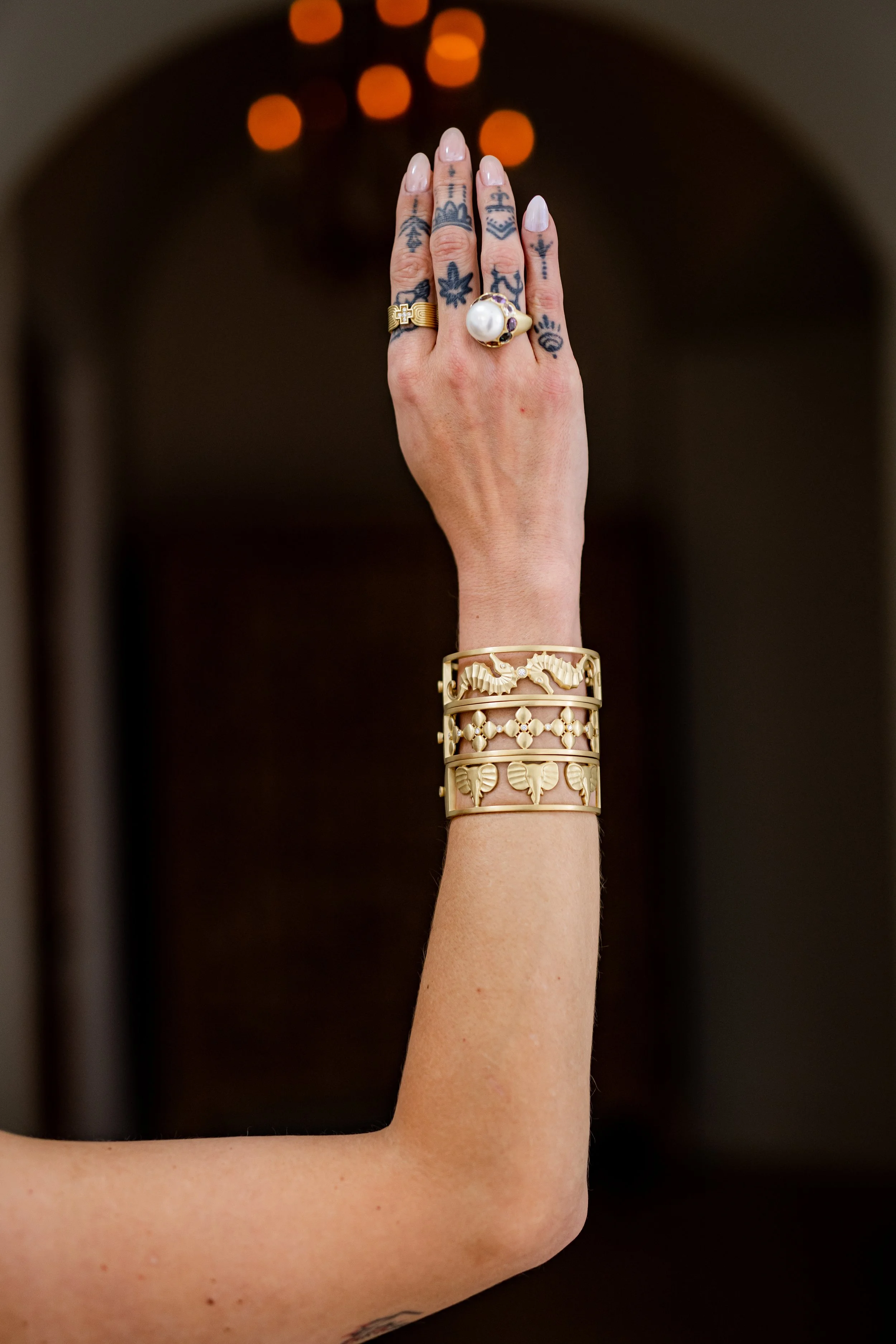 Model wearing Leigh Maxwell Elephant Frame Bracelet and other gold bracelets