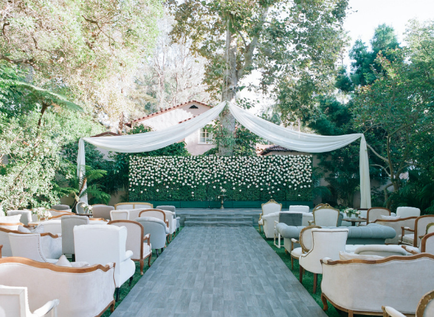 Elegant wedding ceremony with mismatched love seats, vintage chairs, and couches for a comfortable and unique ceremony seating setup. 