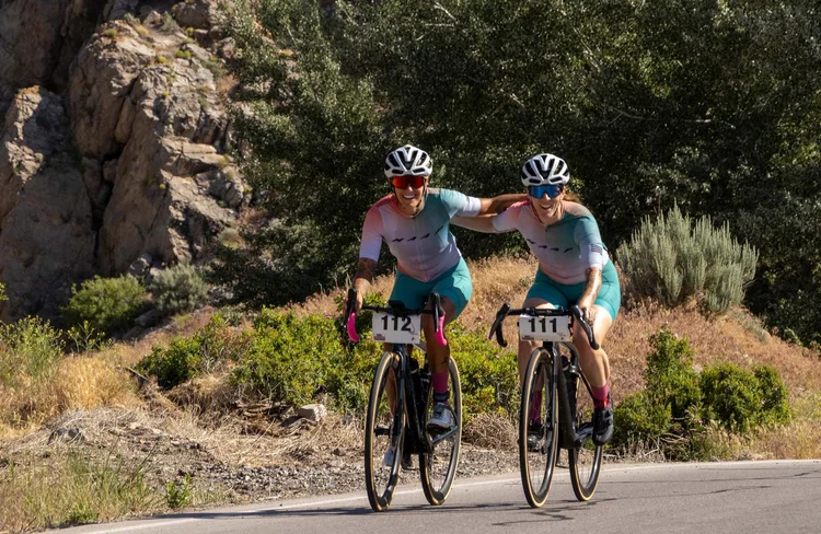 2 female cyclists  dressed in colorful apparel compete at Gran Fondo Utah on a bright summer day