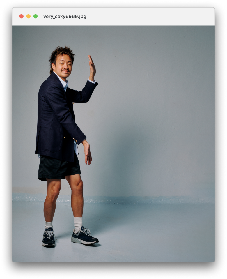 Jordan Leung in a suit jacket, shorts, and sneakers posing in front of a plain gray background.