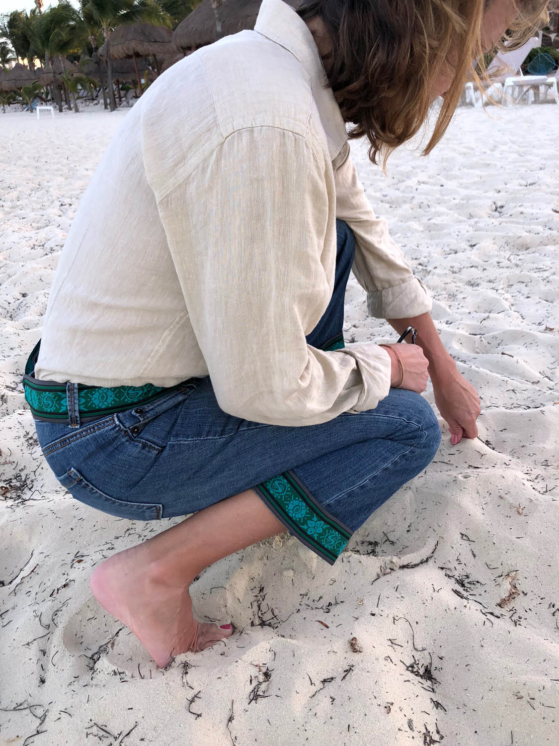 kneeling in the sand with embellished jeans
