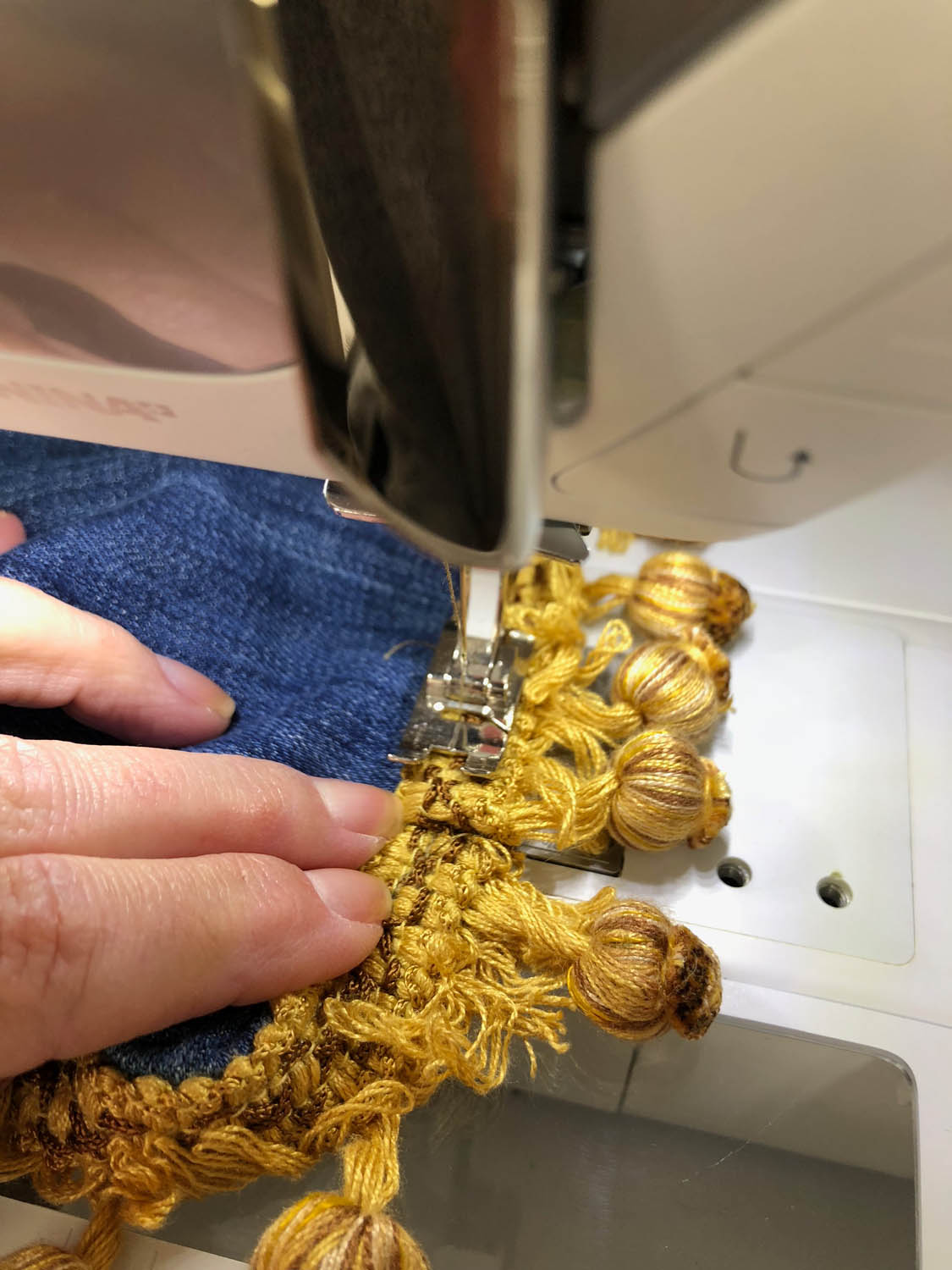 sewing gold upholstery trim to denim blue jeans hem