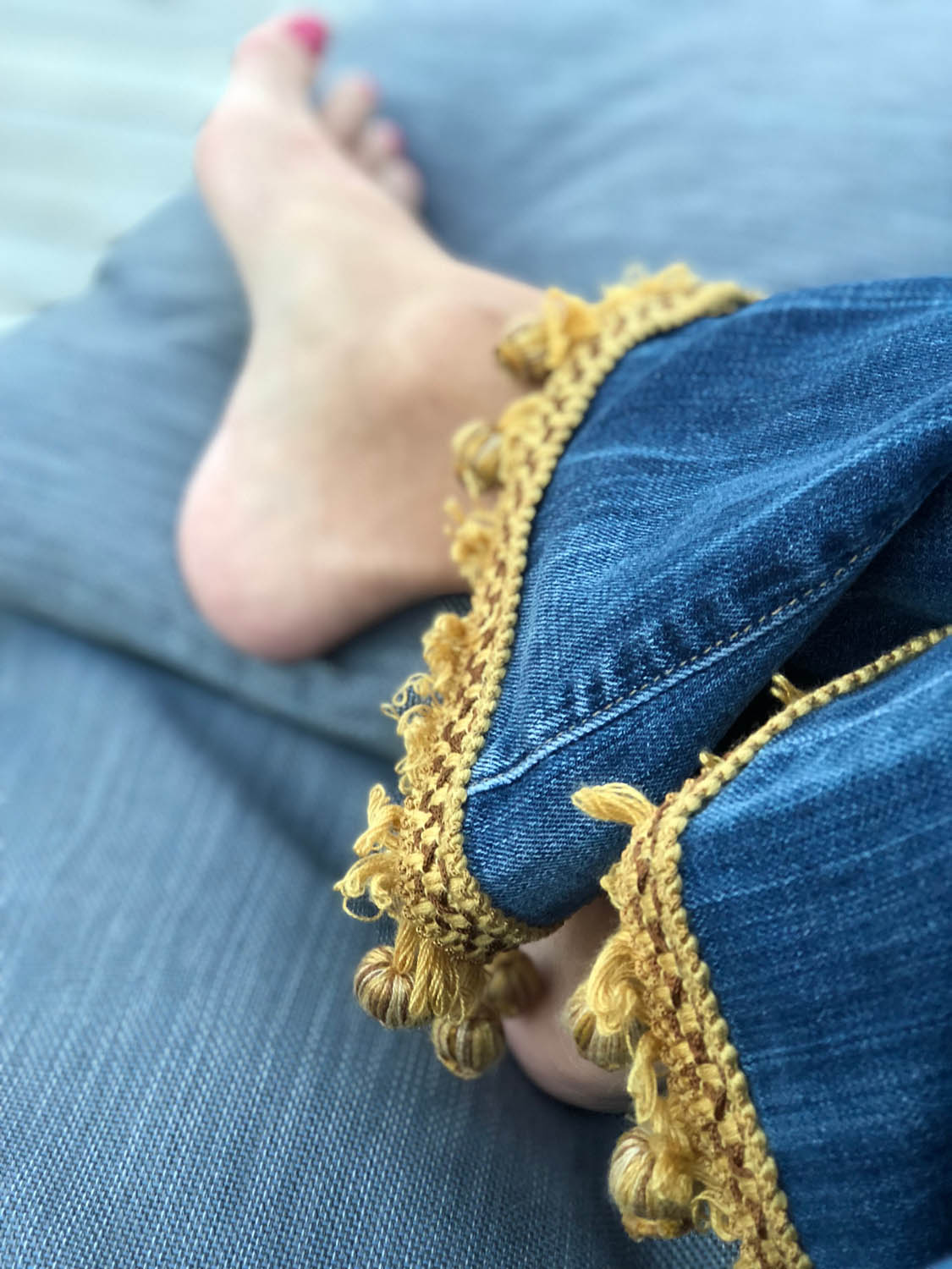 sitting on sofa in gold trim embellished denim blue jeans