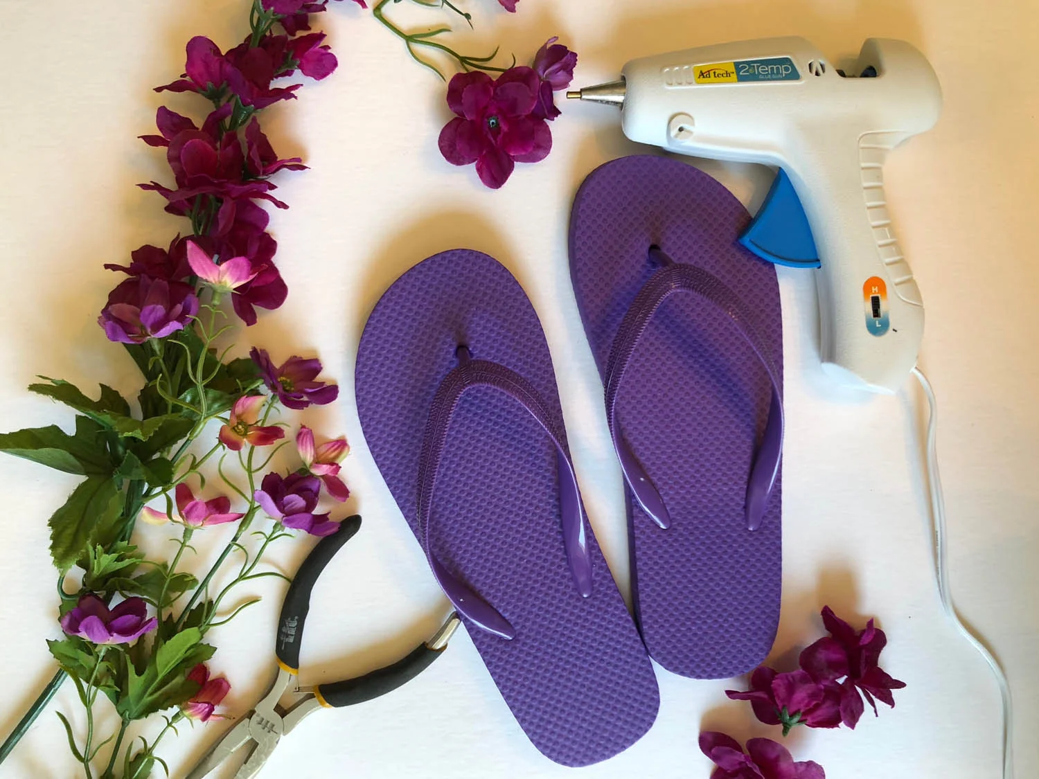 Silk flower stems, wire cutters, glue gun and flip flops to embellish flip flops with silk flowers