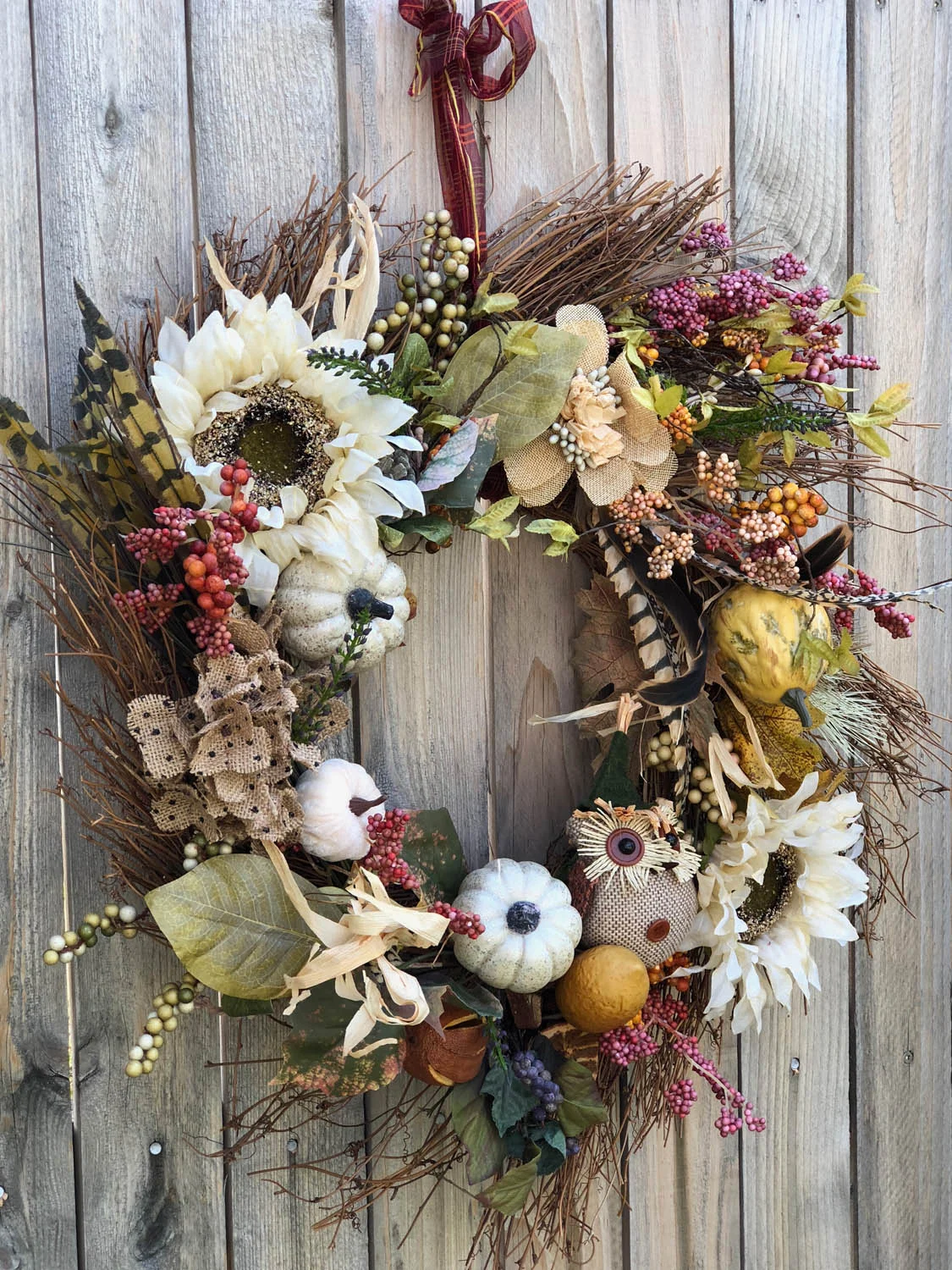 Finished hand made fall wreath hanging on wooden fence outside.
