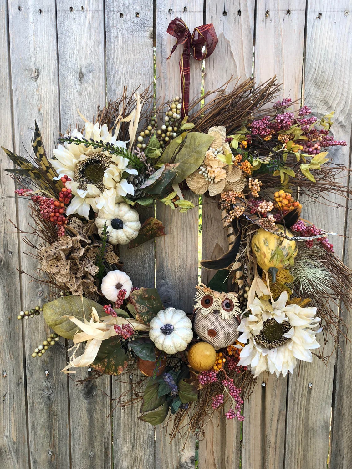 Finished hand made fall wreath hanging on a fence outside.
