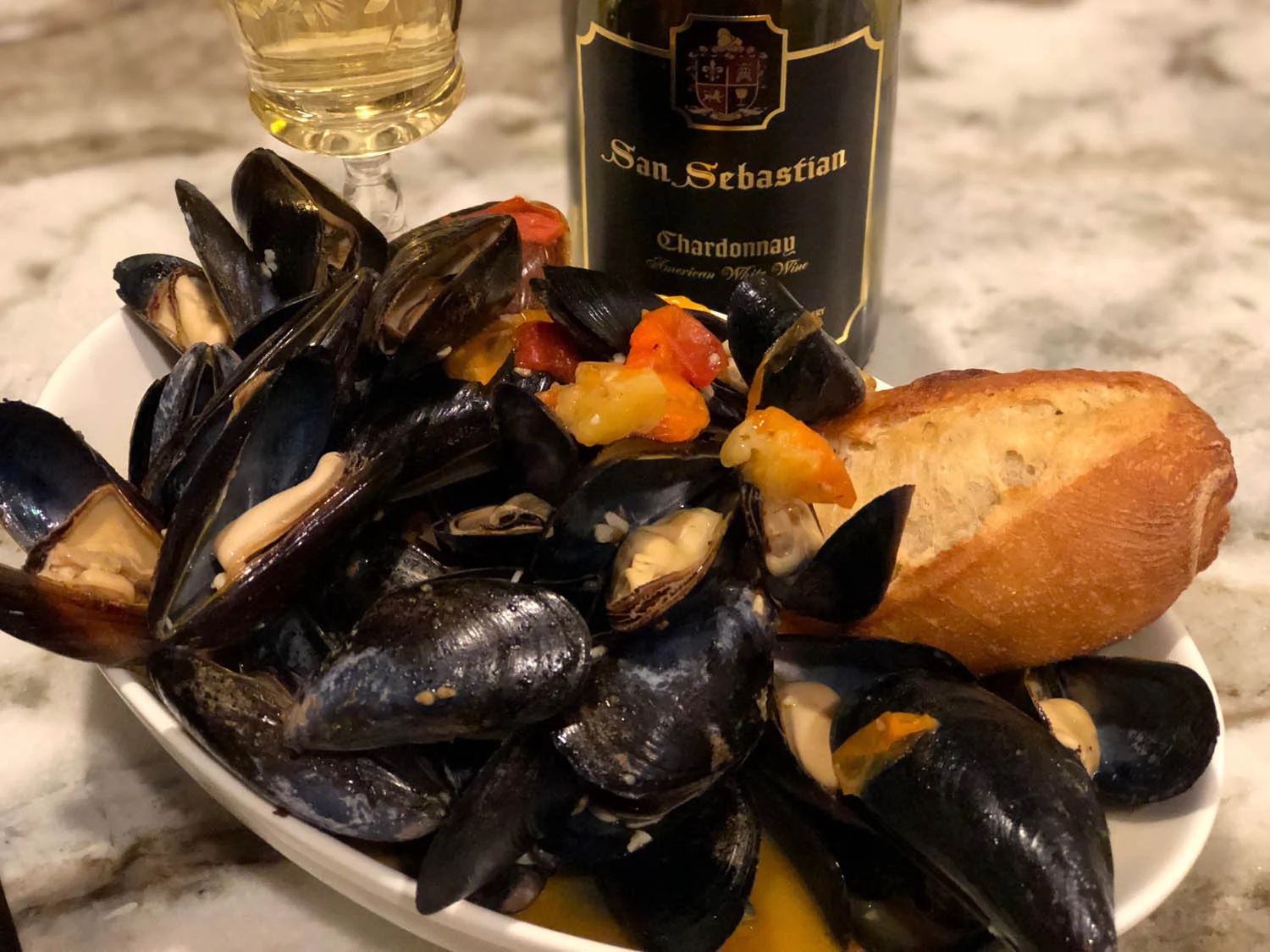 Finished savory mussels with tomatoes and white wine recipe plated and served with fresh, crusty bread.