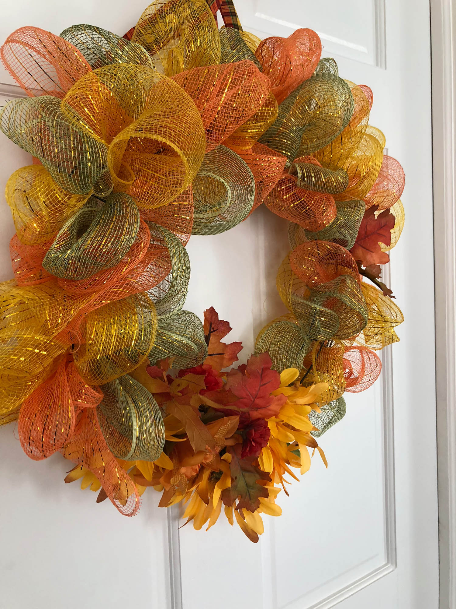 Side view of wired ribbon wrapped wreath hanging on a door