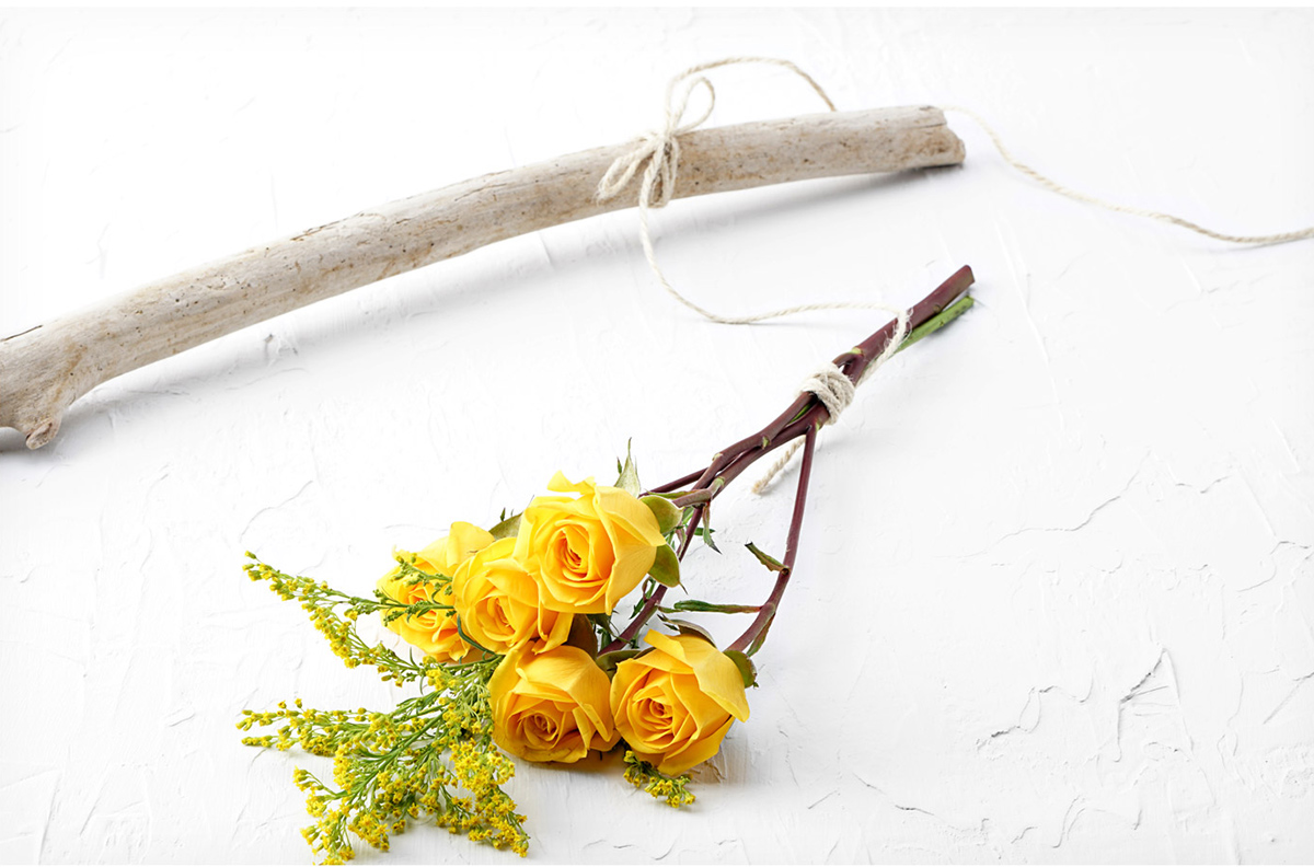 Bundle of fresh flowers tied with string and tied to stick to hang to air dry.