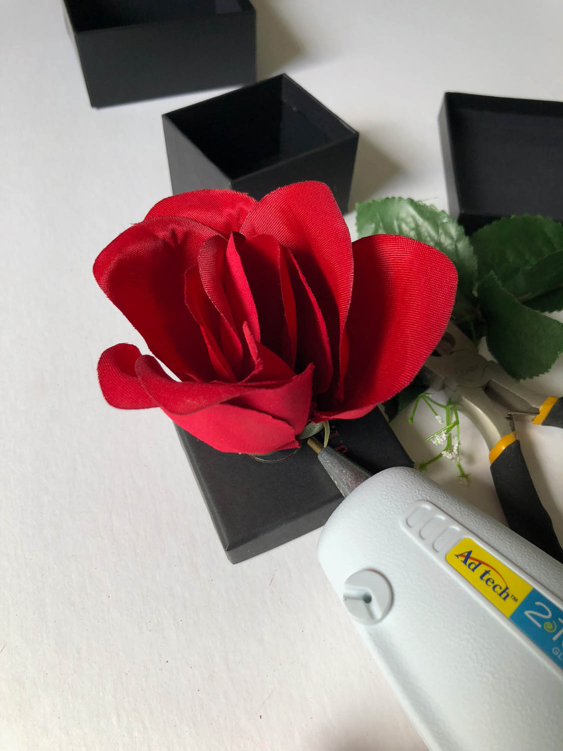 red silk rose pressed into top of small black gift box