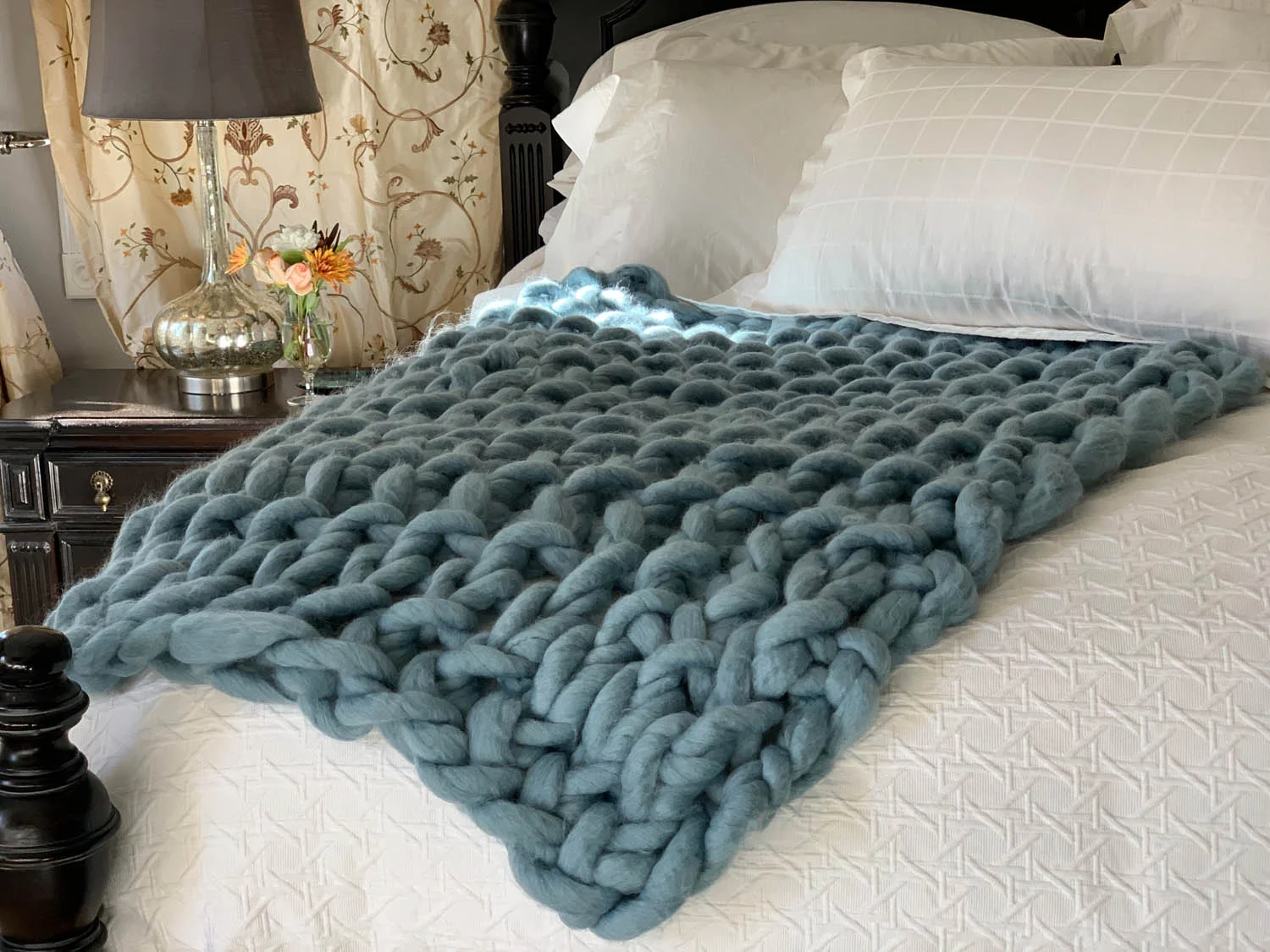 Finished 1 Hour Easy Arm-Knitted Throw in dusty blue on a white bed