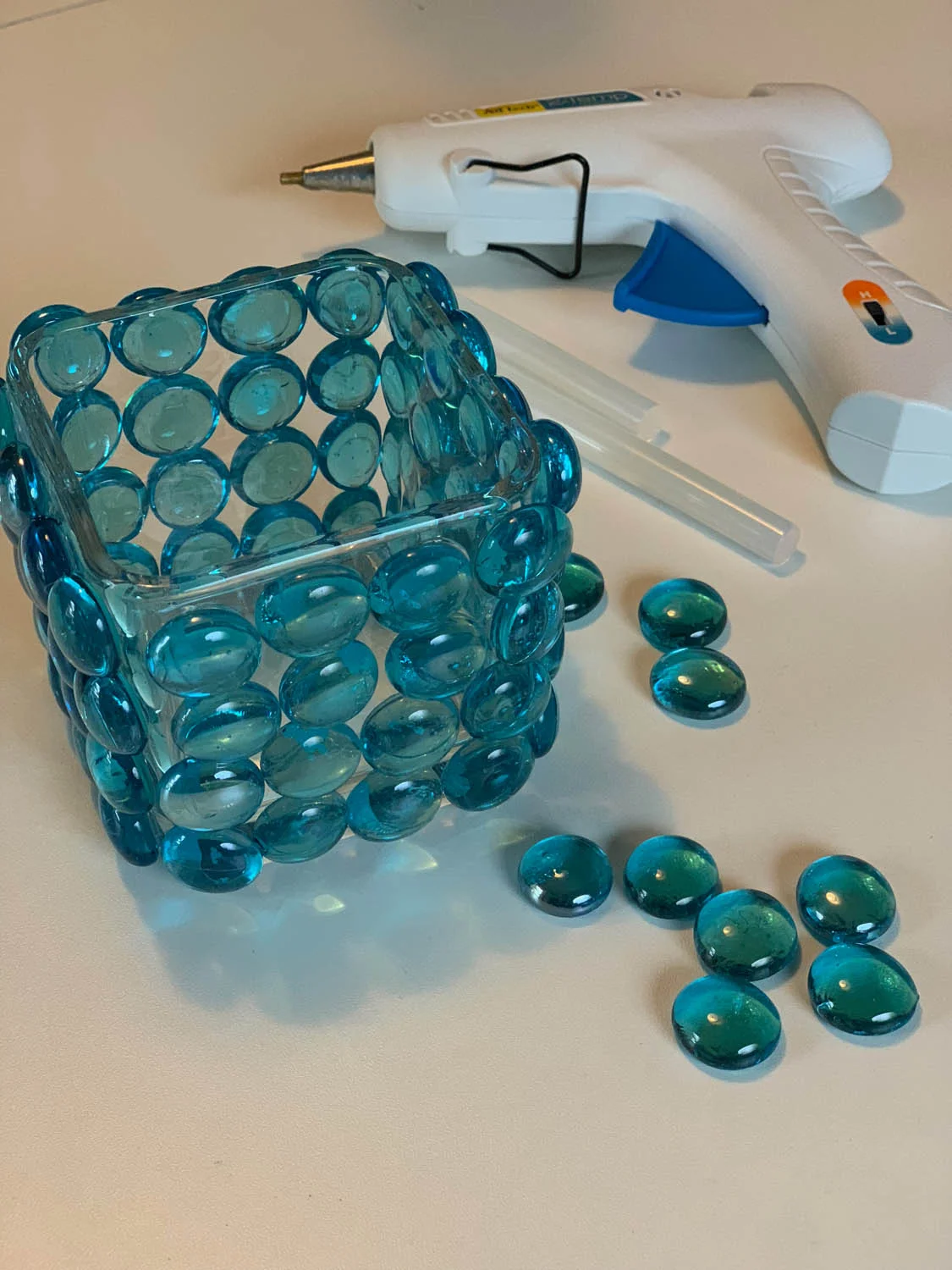 Decorative glass vase covered with blue marble beads with a glue gun