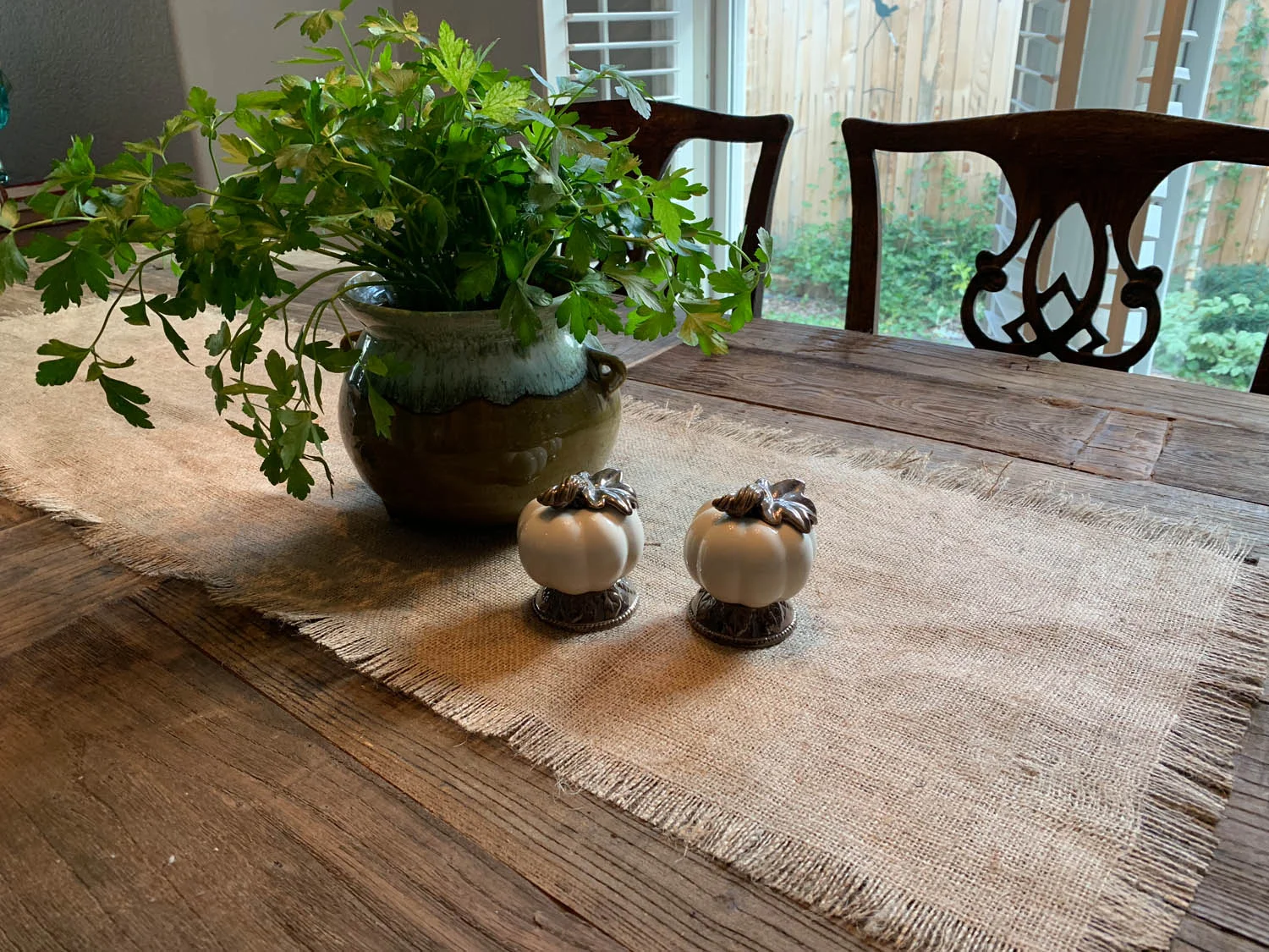 Rustic farmhouse table with burlap table runner and decorative plant and pumkins